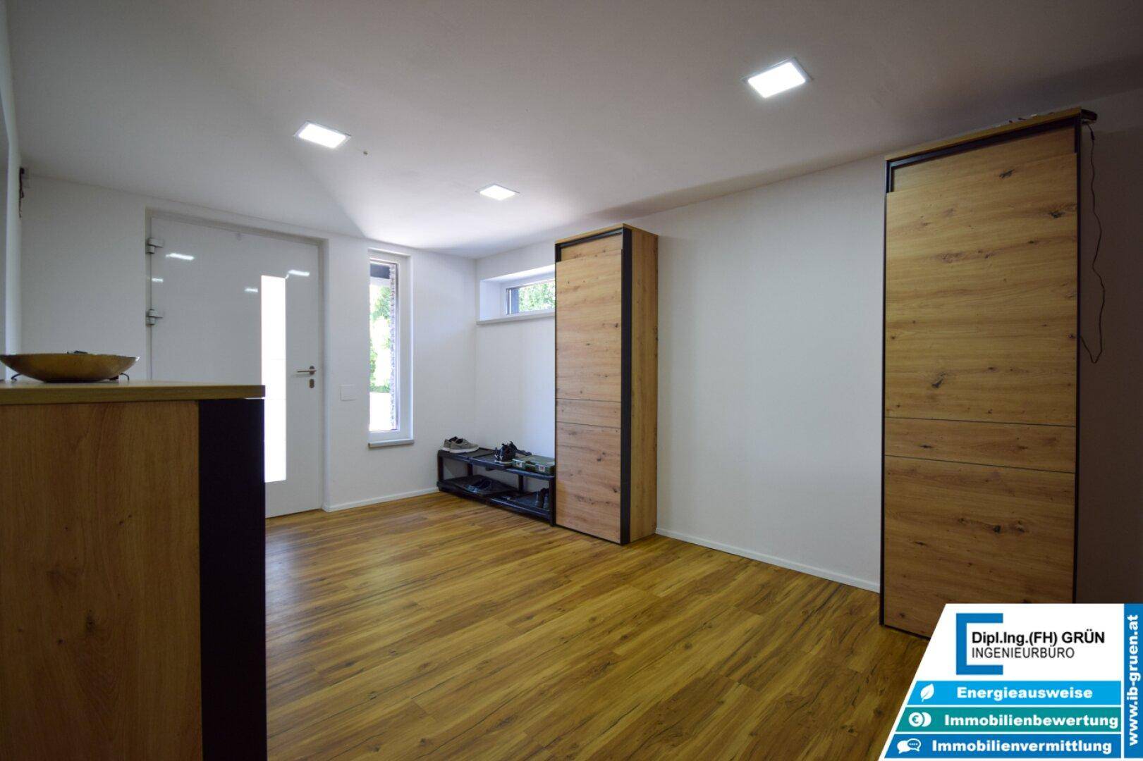 Geräumiger Eingangsbereich mit Holzfußboden und modernen Garderobenschränken in Holzoptik.