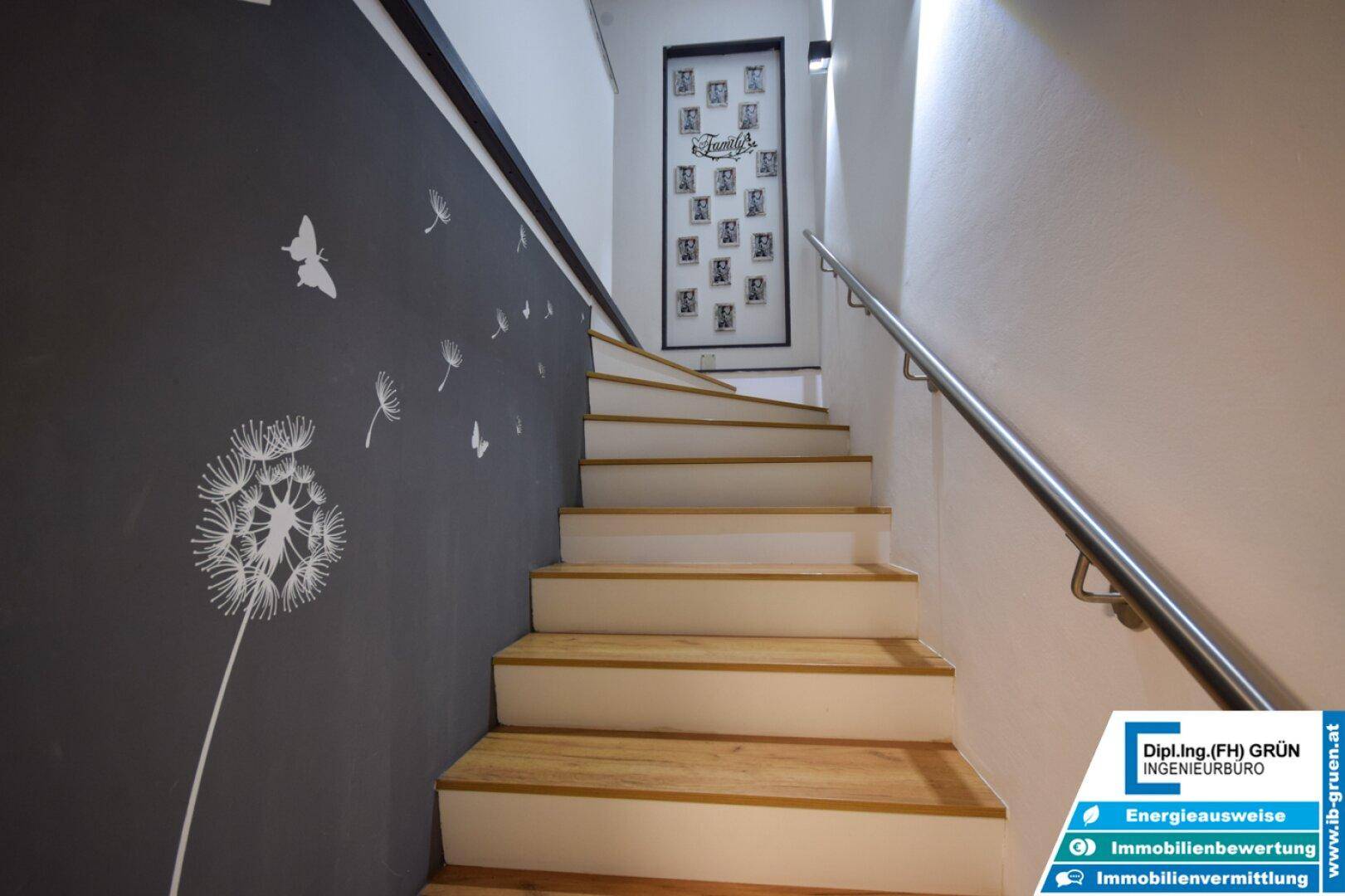 Moderne Holztreppe mit Edelstahlgeländer und dekorativer Wandgestaltung im Treppenhaus.