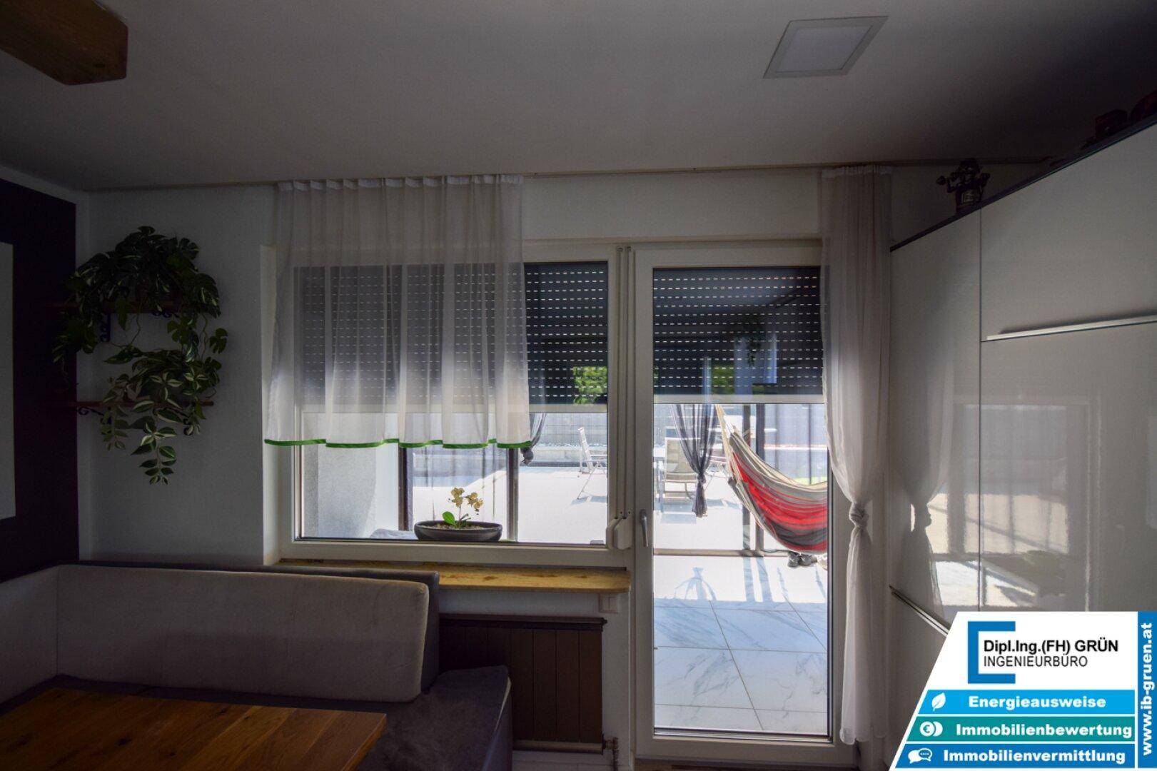 Fenster und Terrassentür mit Rollladen, die den Blick auf den Außenbereich und eine Hängematte freigeben.