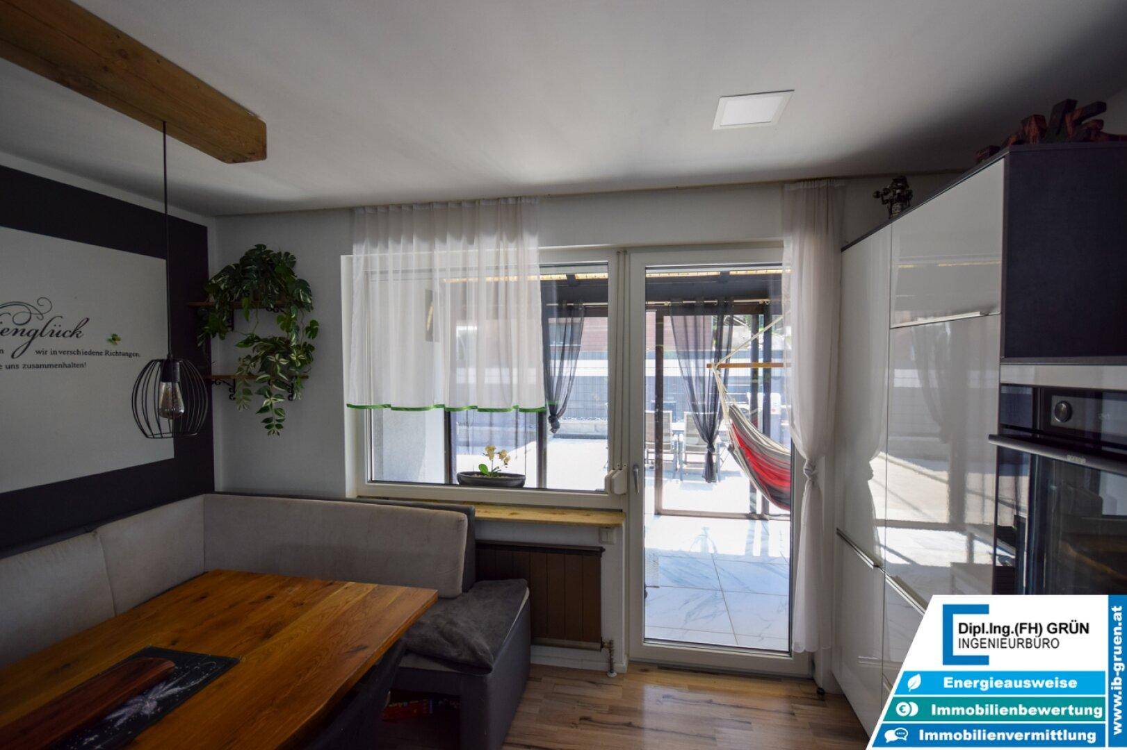 Heller Essbereich mit Fenster und Terrassentür, die den Blick nach draußen auf die Terrasse freigibt.