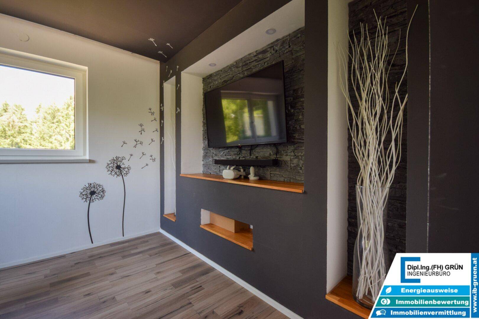 Wohnzimmerwand mit montiertem Fernseher, dekorativer Steinverkleidung und integrierten Regalen.