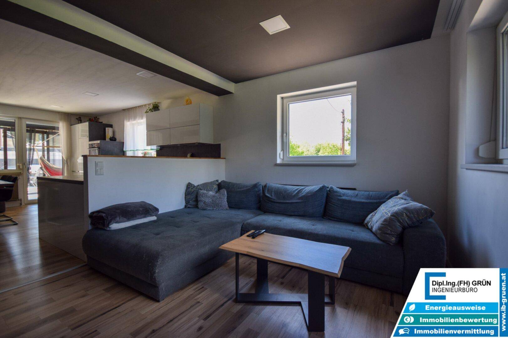 Helles Wohnzimmer mit großem Sofa und offener Verbindung zur Küche, ideal für geselliges Beisammensein.