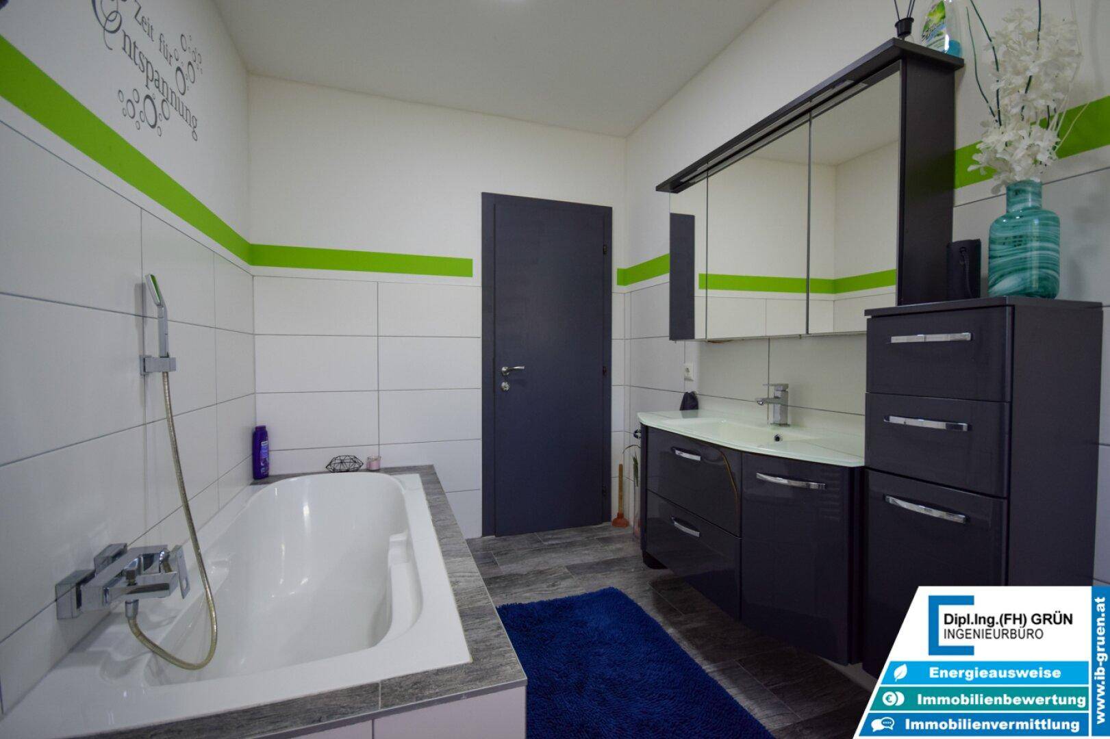 Badezimmer mit Badewanne, modernem Waschtisch und Spiegelschrank in dunklem Design.