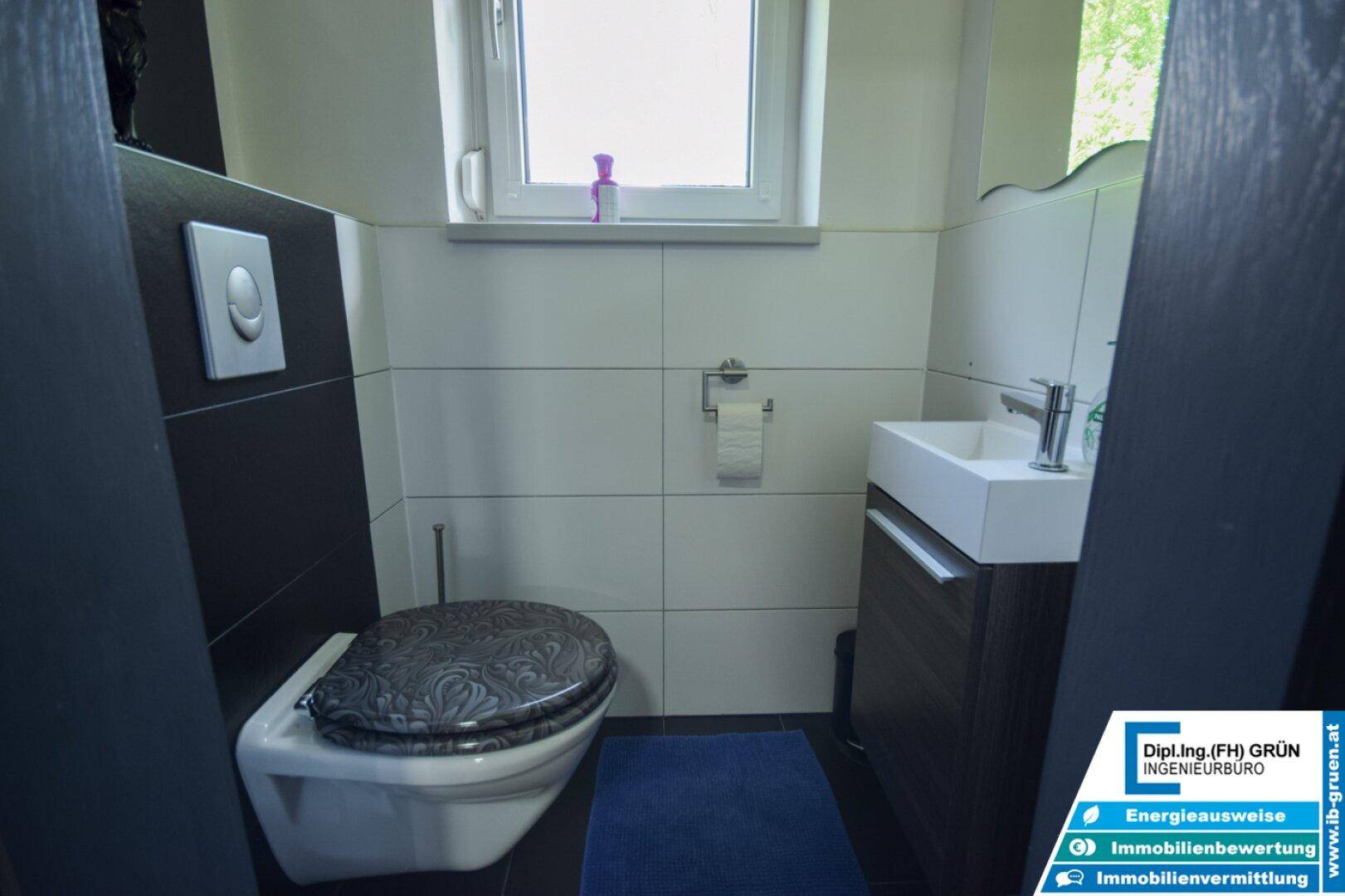 Kleines Gäste-WC mit wandhängender Toilette, Waschbecken und Fenster.