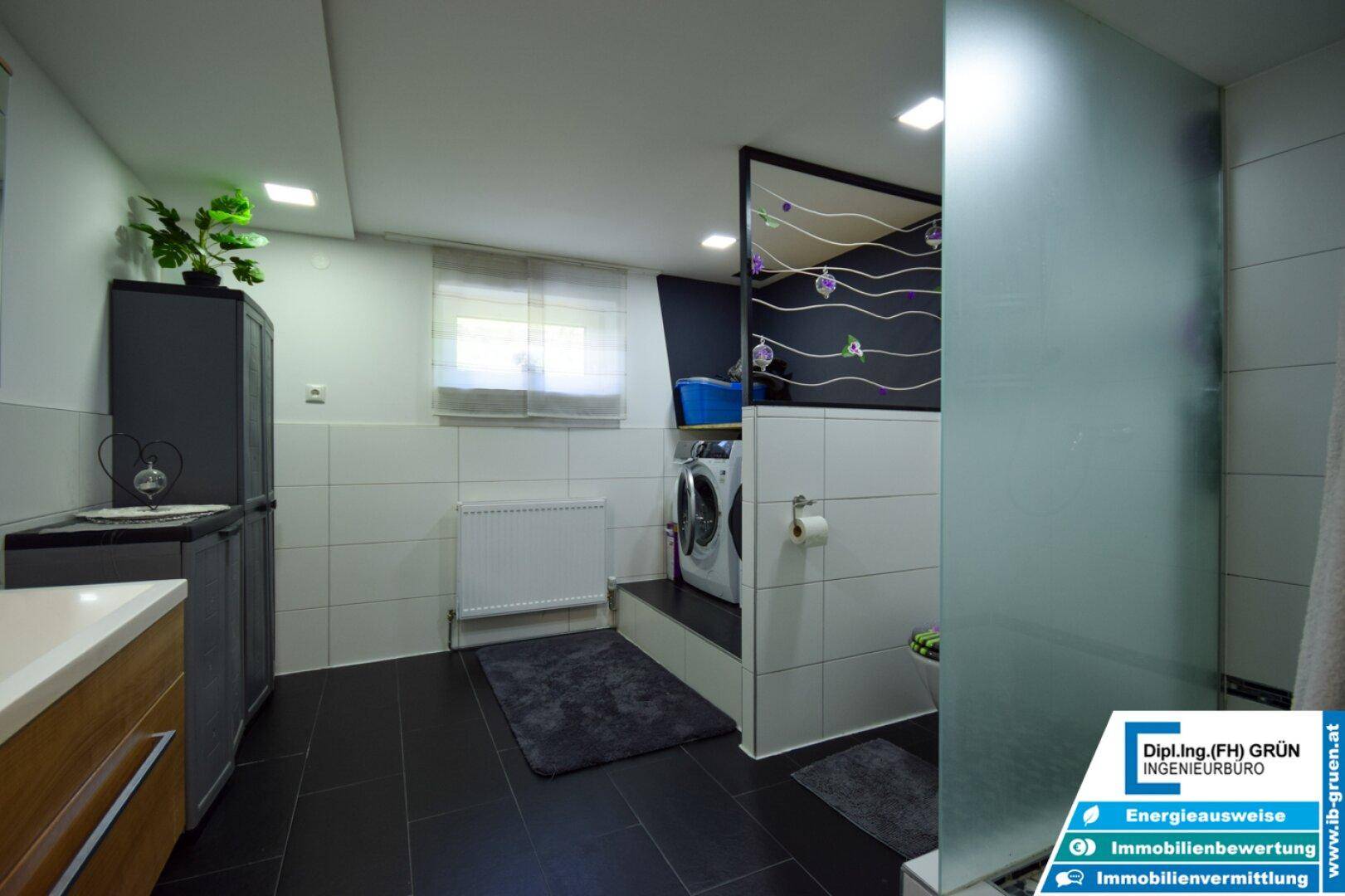 Modernes Badezimmer im Untergeschoss mit Dusche, Waschmaschine und Trockner.