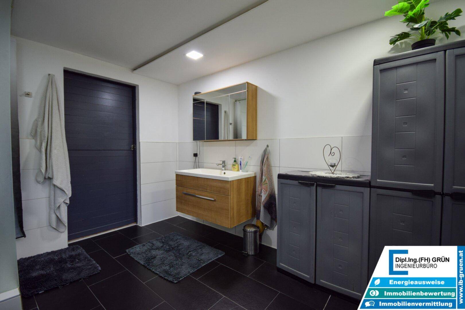 Badezimmer im Untergeschoss mit Waschtisch, Spiegelschrank und praktischen Schränken.