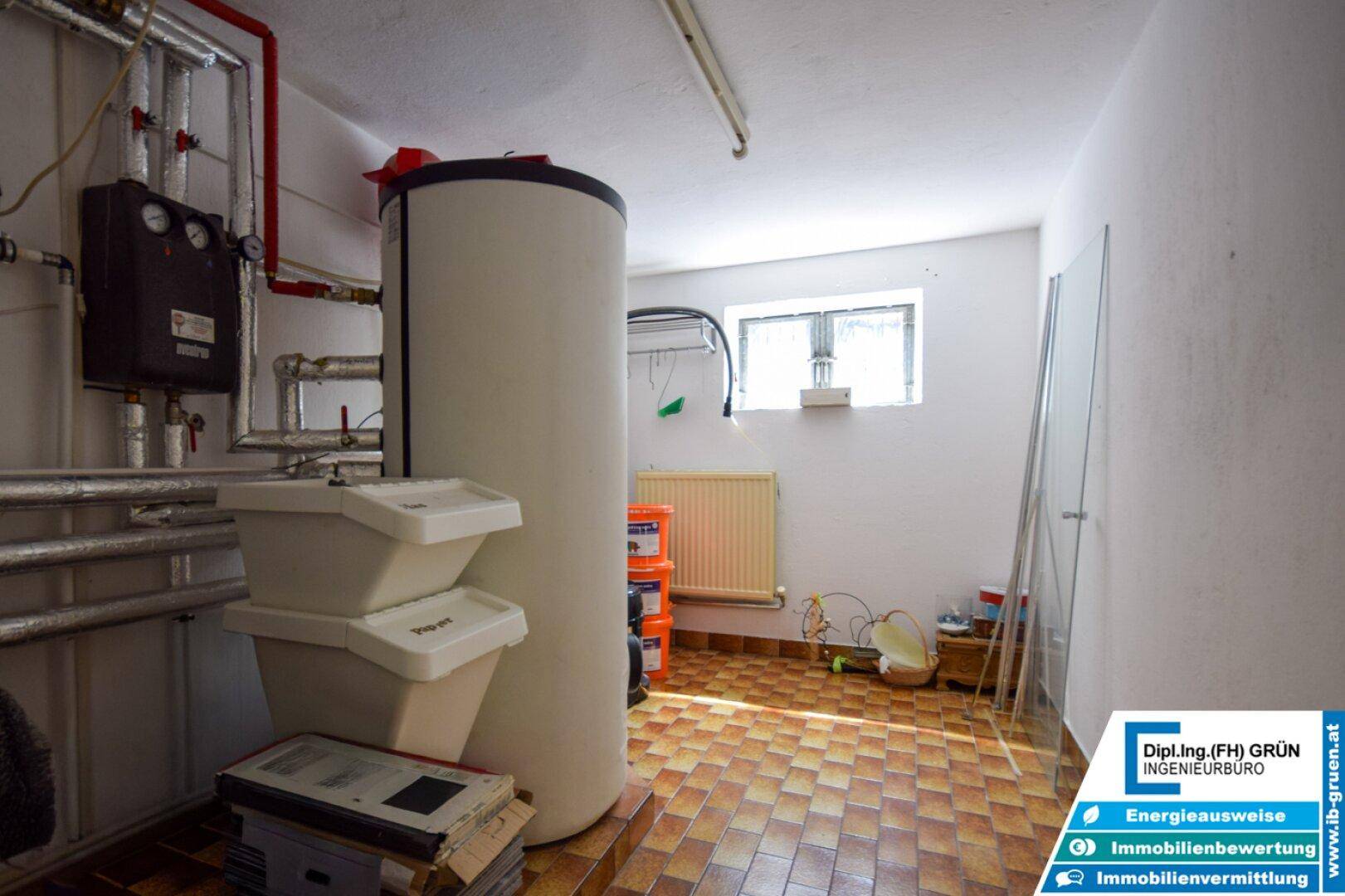 Heizungsraum im Keller mit Warmwasserspeicher und technischen Installationen.