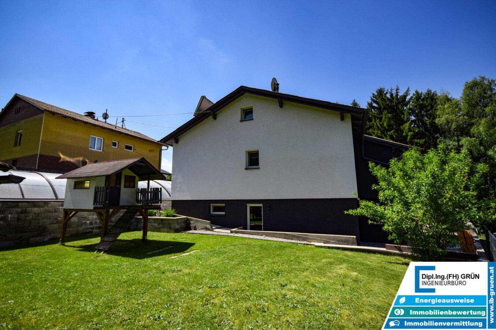 Rückansicht des Hauses mit großem Garten, Baumhaus und angrenzendem Gebäude.