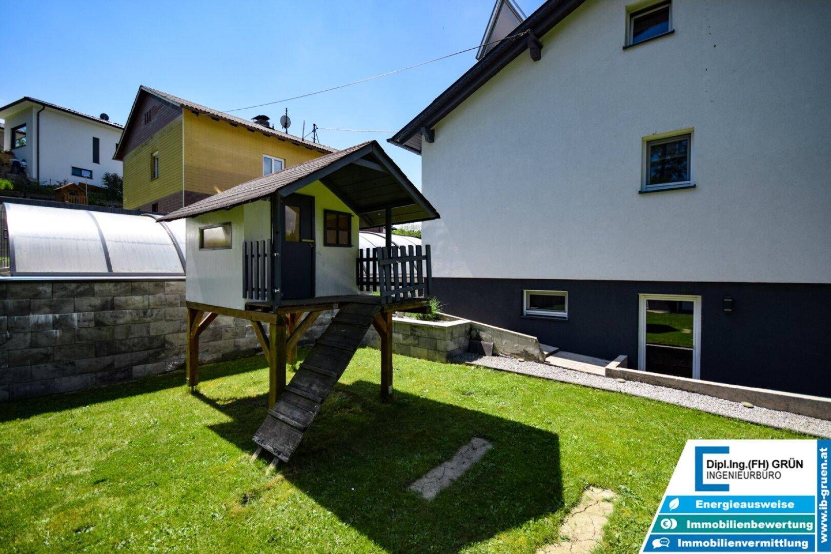 Detailansicht des Baumhauses im Garten mit Treppe und umliegender Rasenfläche.