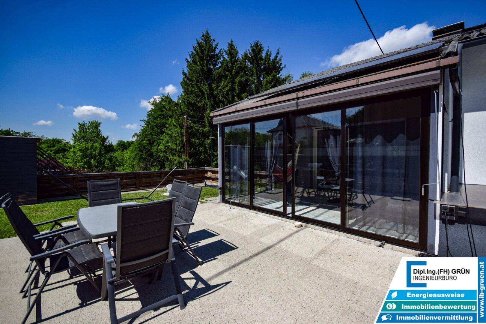 Gemütliche Terrasse mit Esstisch und Stühlen, direkt am verglasten Wintergarten gelegen.