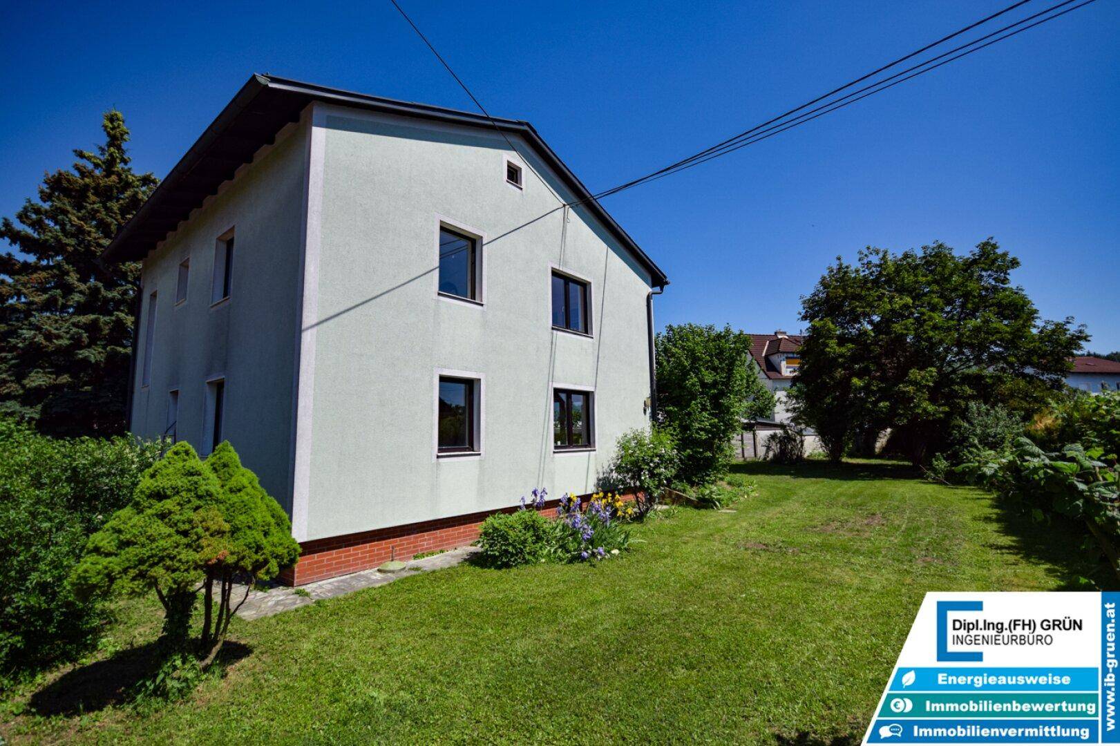 Seitenansicht des Hauses mit gepflegtem Garten und blühenden Pflanzen.
