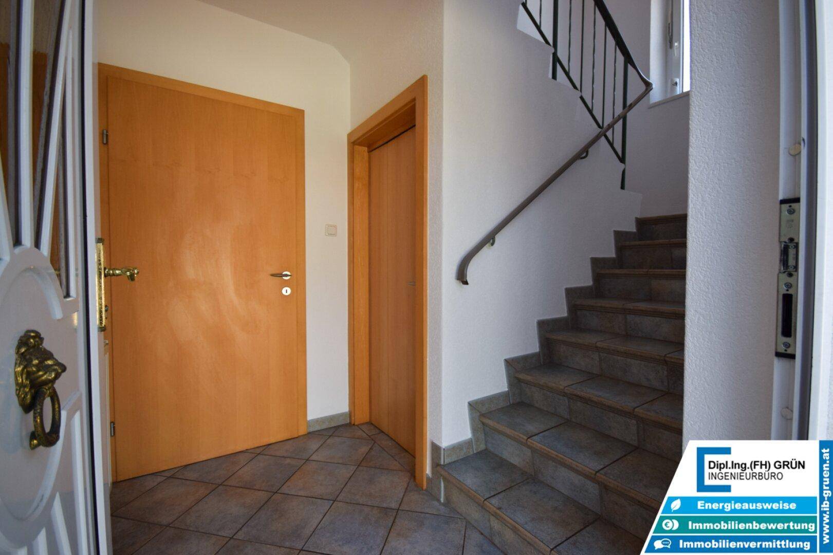 Heller Eingangsbereich mit gefliestem Boden und Treppe zum Obergeschoss.