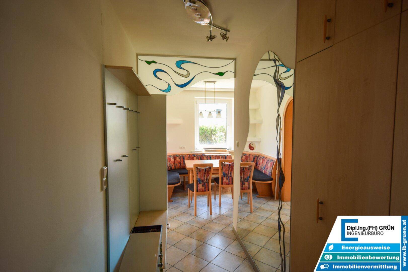 Flur mit Einbauschränken und Blick in den Essbereich mit Fenster.