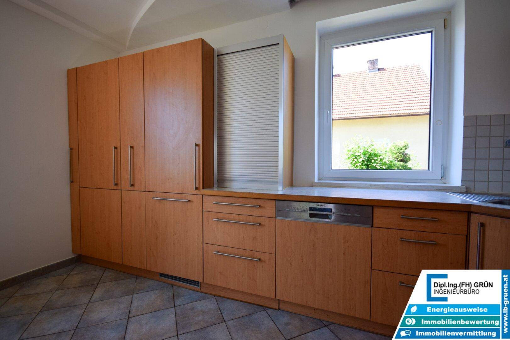 Küchenzeile mit Holzfronten, integriertem Geschirrspüler und Fenster.