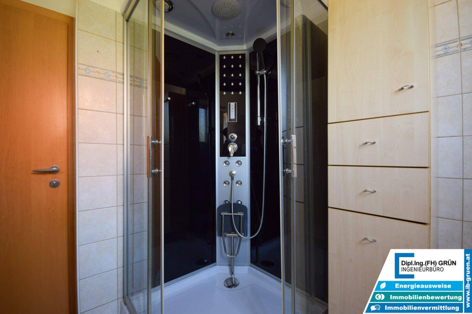 Modernisierte Duschkabine mit Hydro-Massage-Funktion und integrierten Ablagen in einem gefliesten Badezimmer.