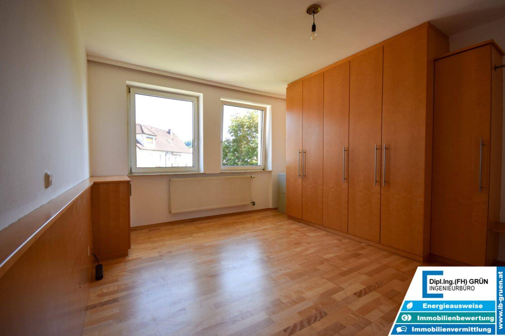Helles Schlafzimmer mit Parkettboden und großem Einbauschrank aus Holz.