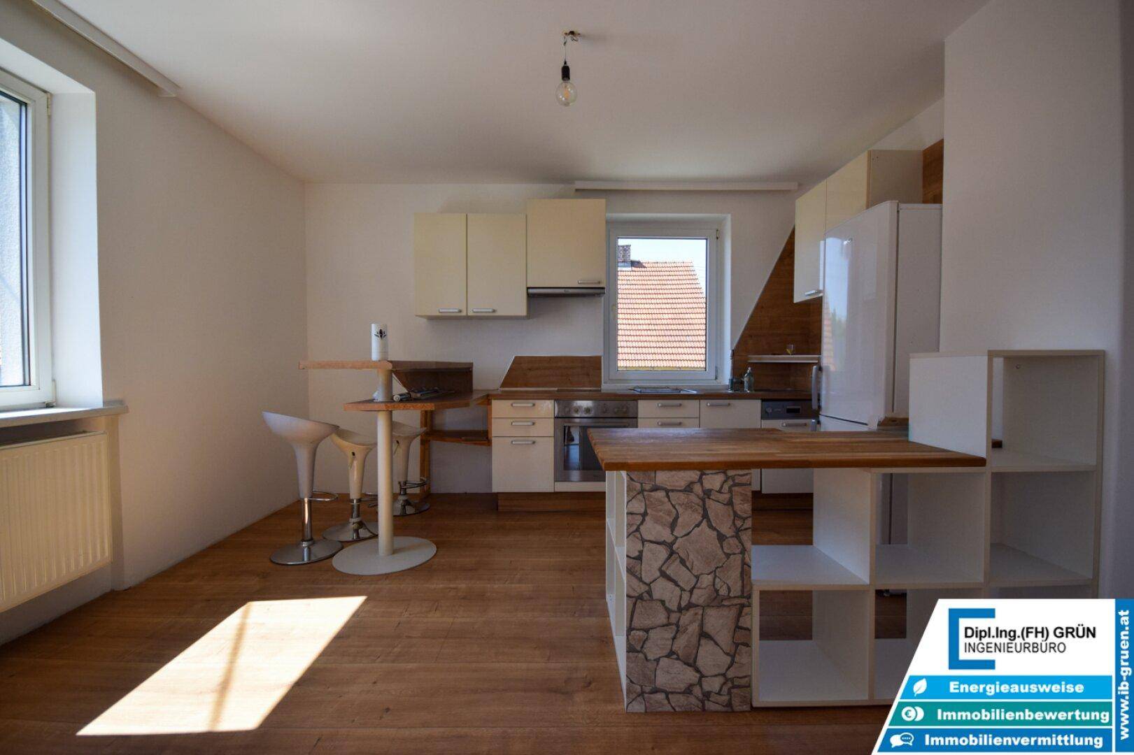 Helle Wohnküche mit Holzboden, Kücheninsel und Bartresen, ideal für geselliges Beisammensein.
