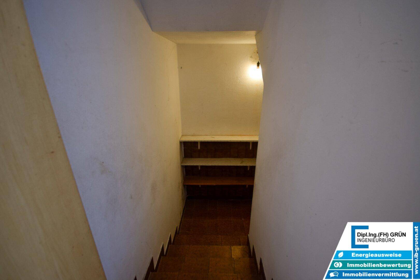 Treppenabgang in den Keller mit Holzstufen und einfacher Beleuchtung.