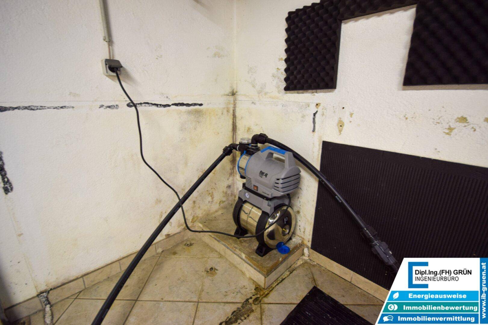 Feuchter Kellerraum mit Wasserpumpe und Schalldämmung an den Wänden.