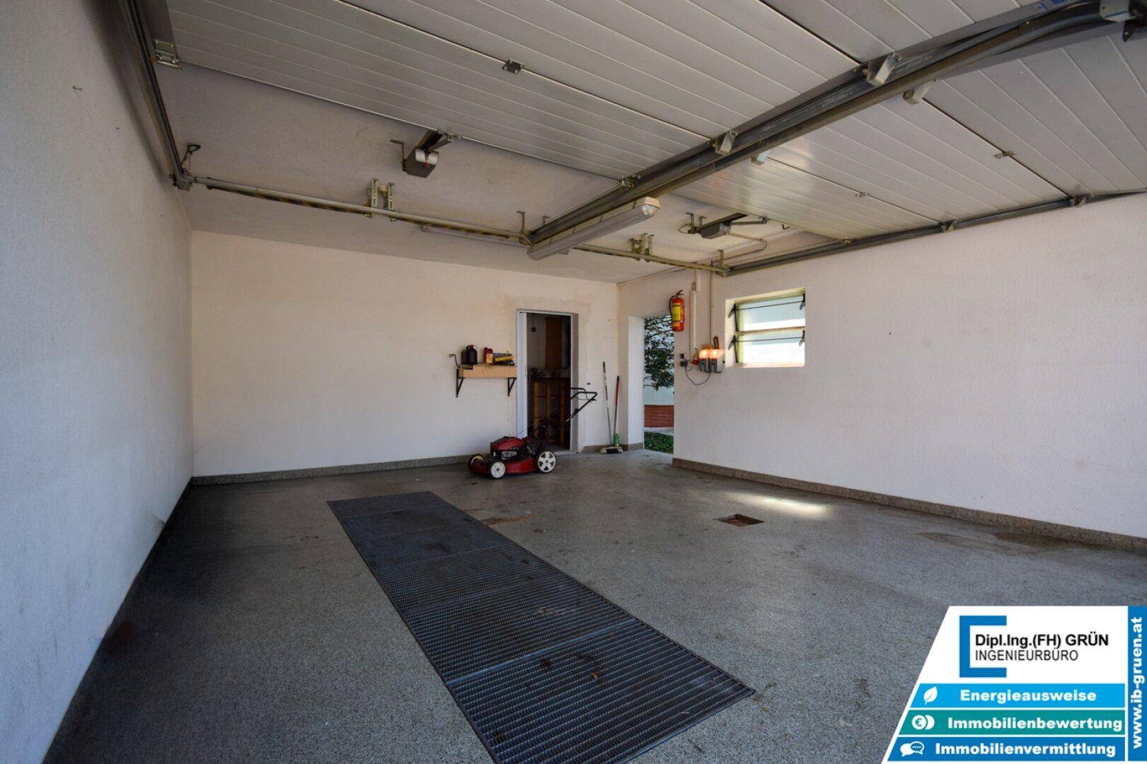 Geräumige Garage mit Betonboden, Fenstern und Platz für Werkzeuge.