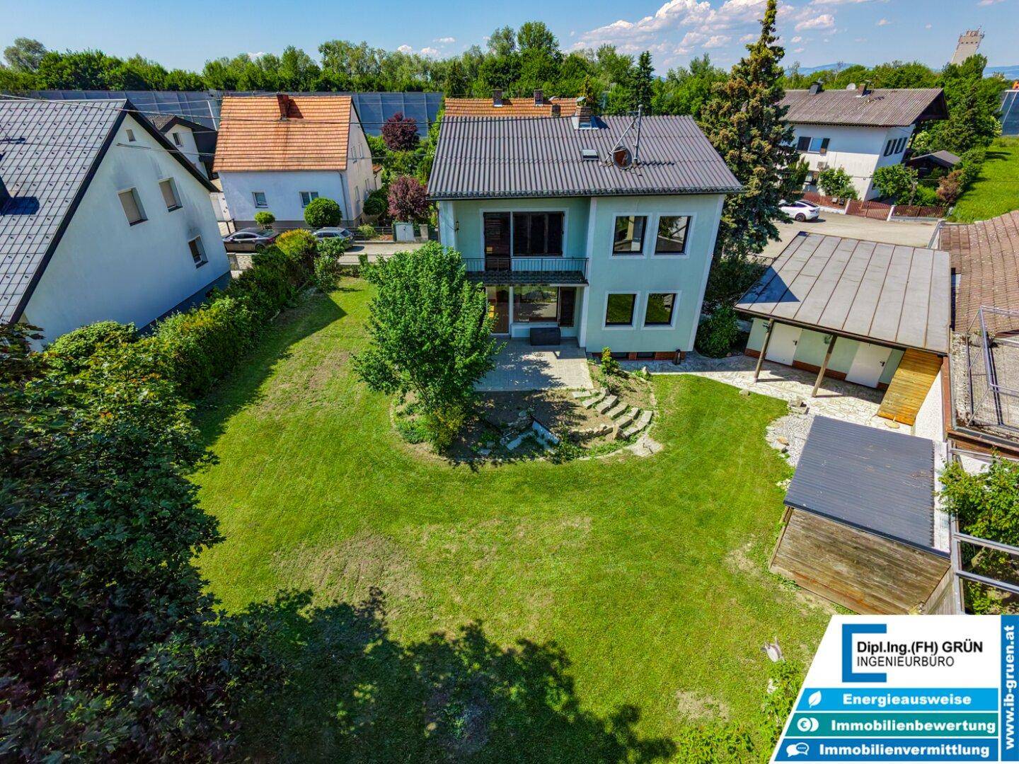 Luftaufnahme des Hauses von hinten mit großem Garten, Schuppen und Balkon.