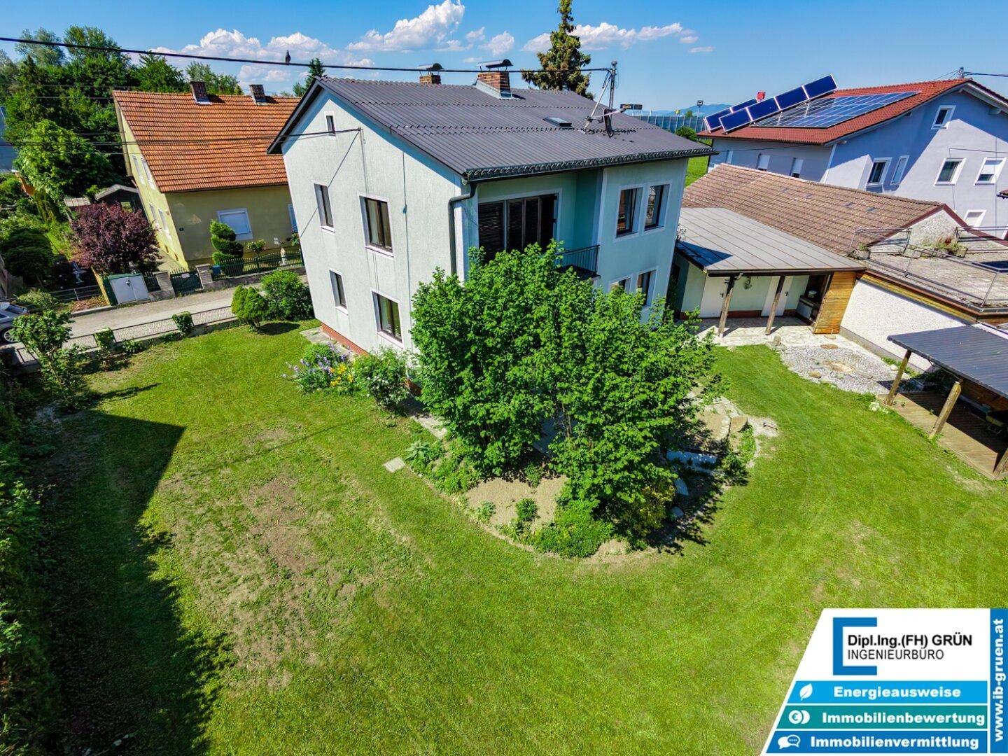 Weitläufiger Gartenbereich hinter dem Haus mit Rasenfläche und Bäumen.