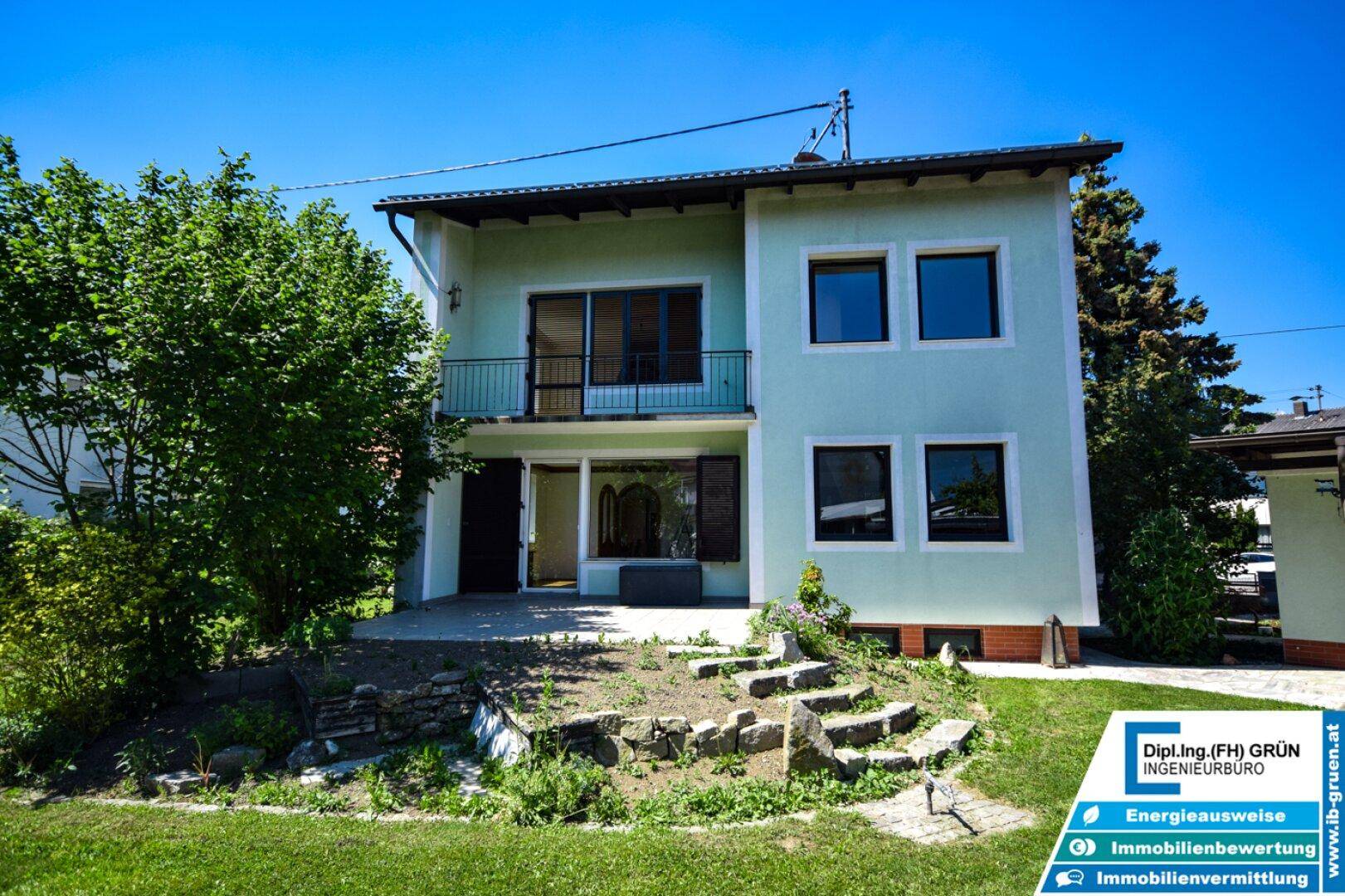Rückansicht des Hauses mit Balkon, Terrassenbereich und Treppe zum Garten.
