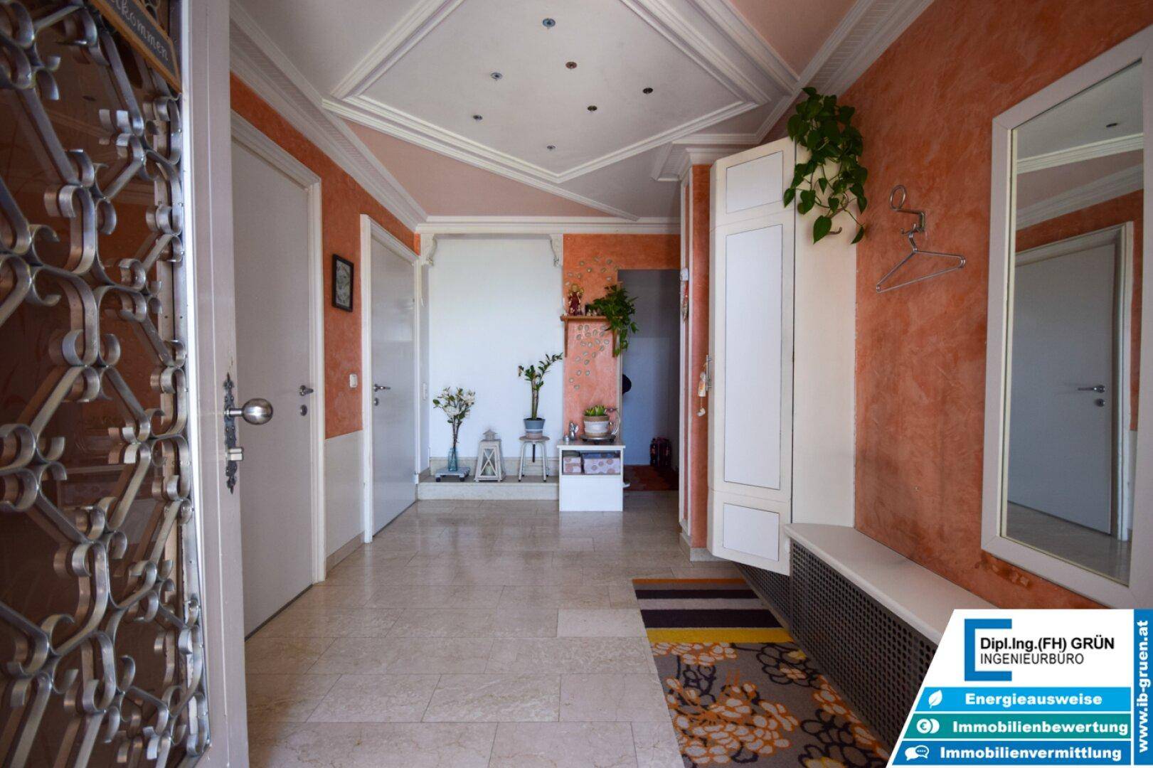 Heller Flur mit Stuckdecke, gemustertem Teppich und Spiegel an der Wand.