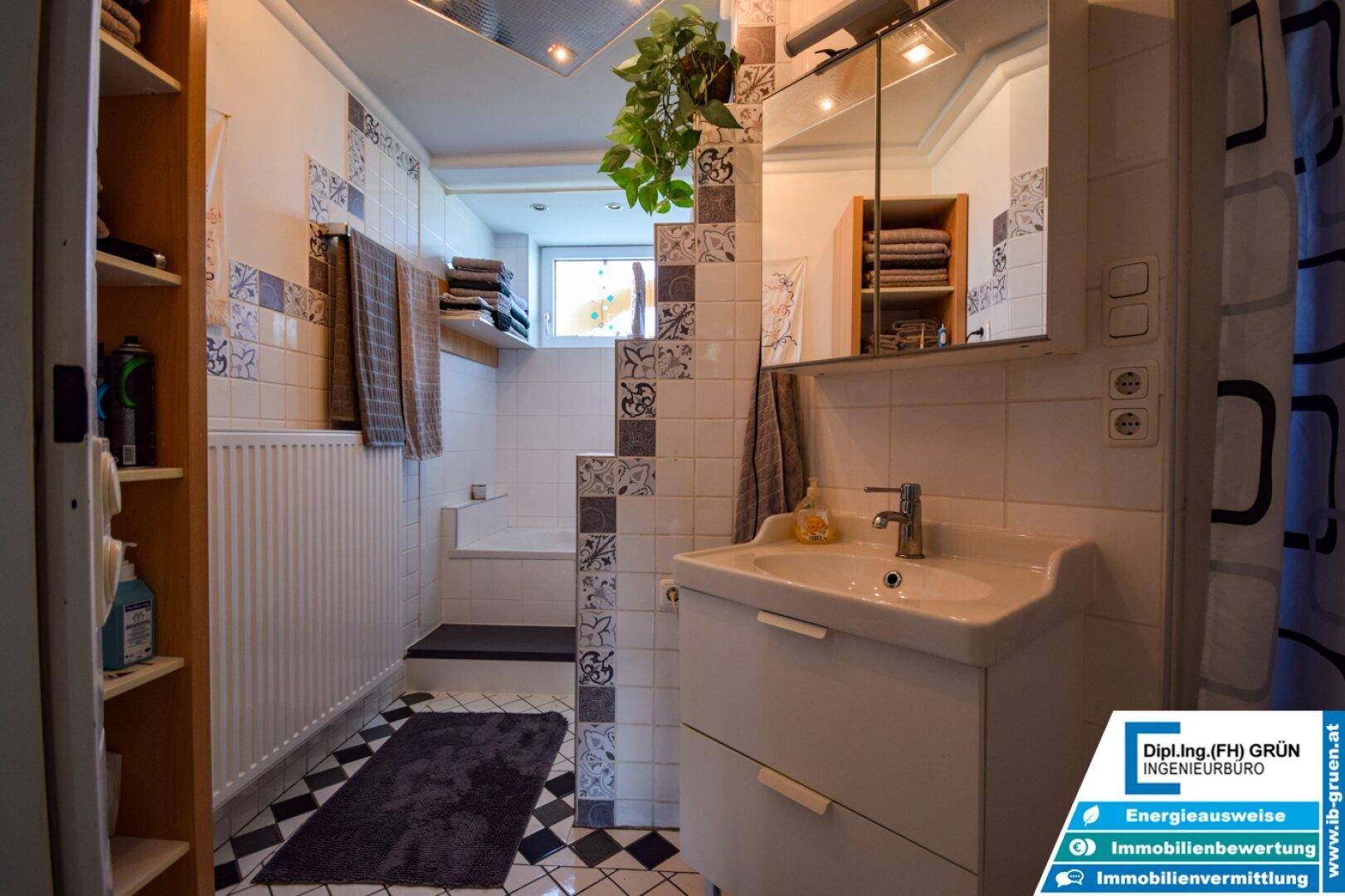 Badezimmer mit Badewanne, Waschbecken und gemusterten Fliesen in Weiß und Blau.