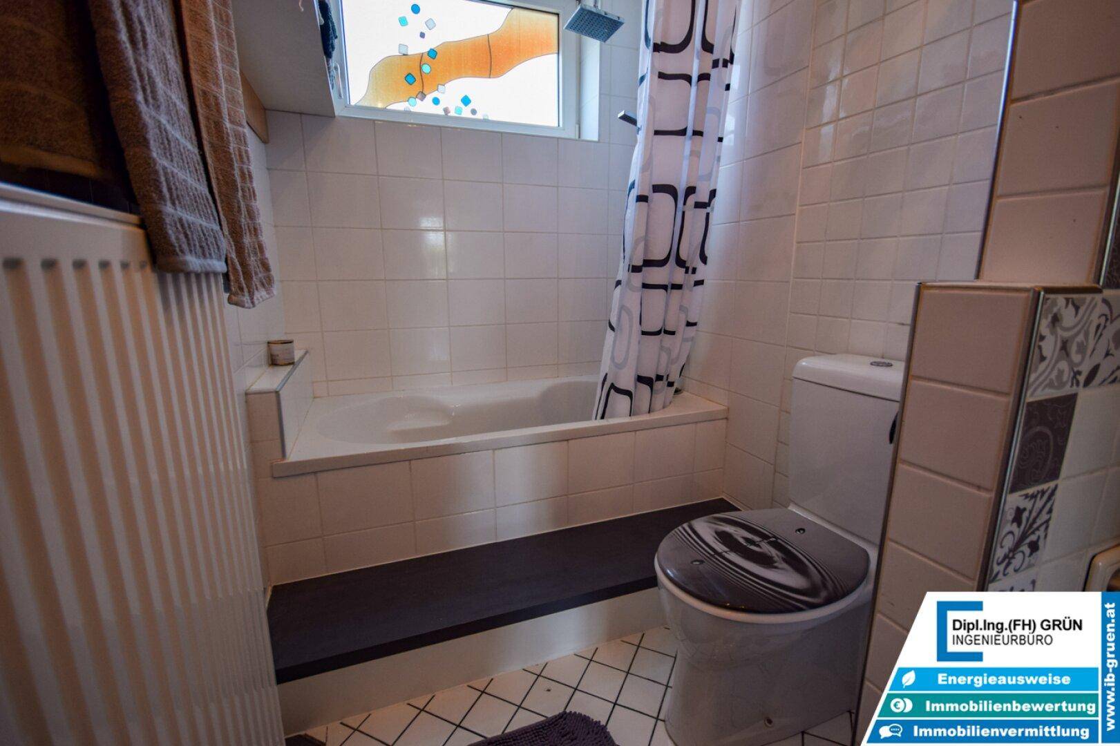 Badezimmerbereich mit Badewanne, Duschvorhang und Toilette mit gemustertem Deckel.