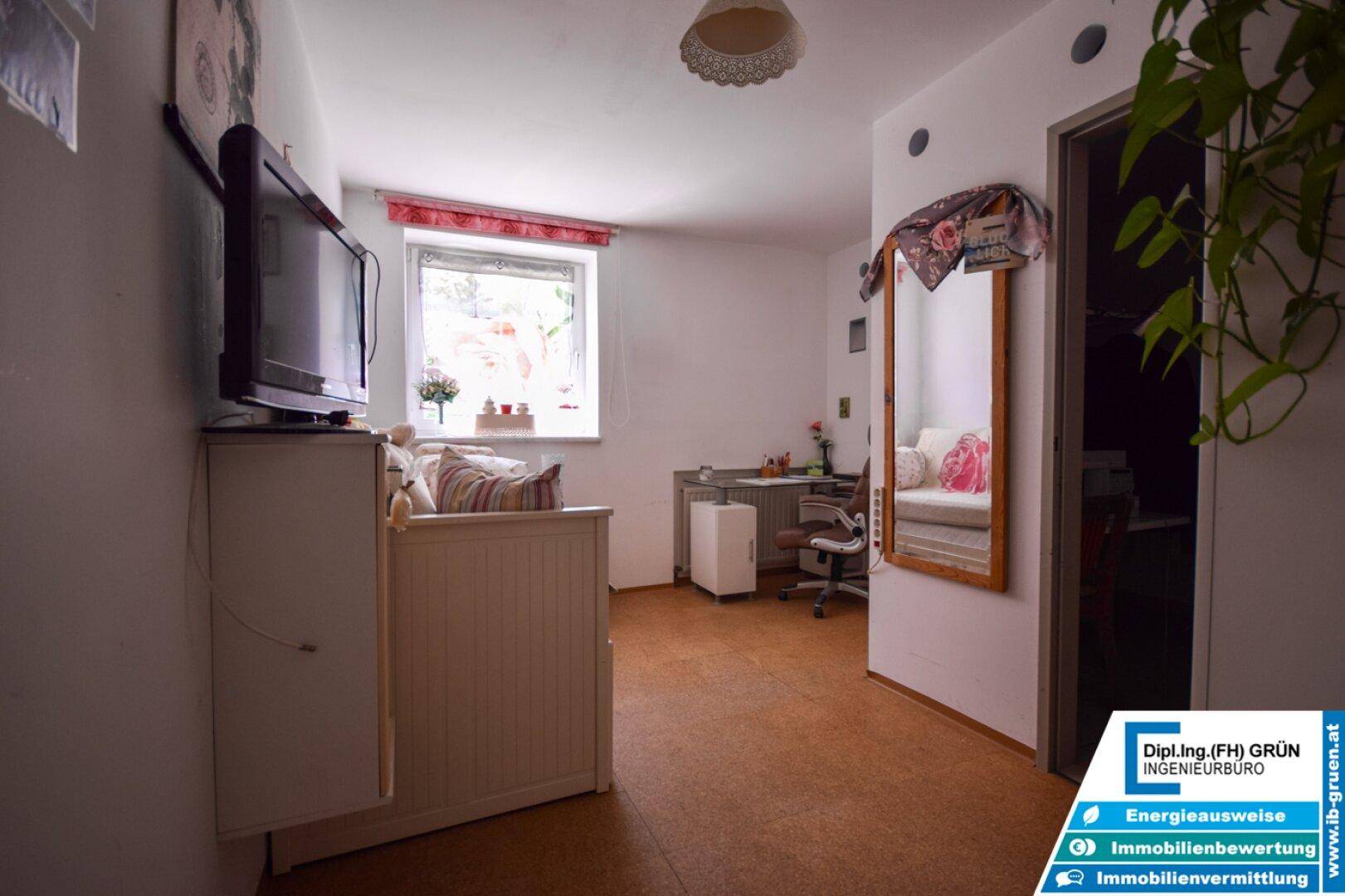 Kleines Zimmer mit Fenster, Bett und Schreibtisch, ideal als Kinder- oder Gästezimmer.