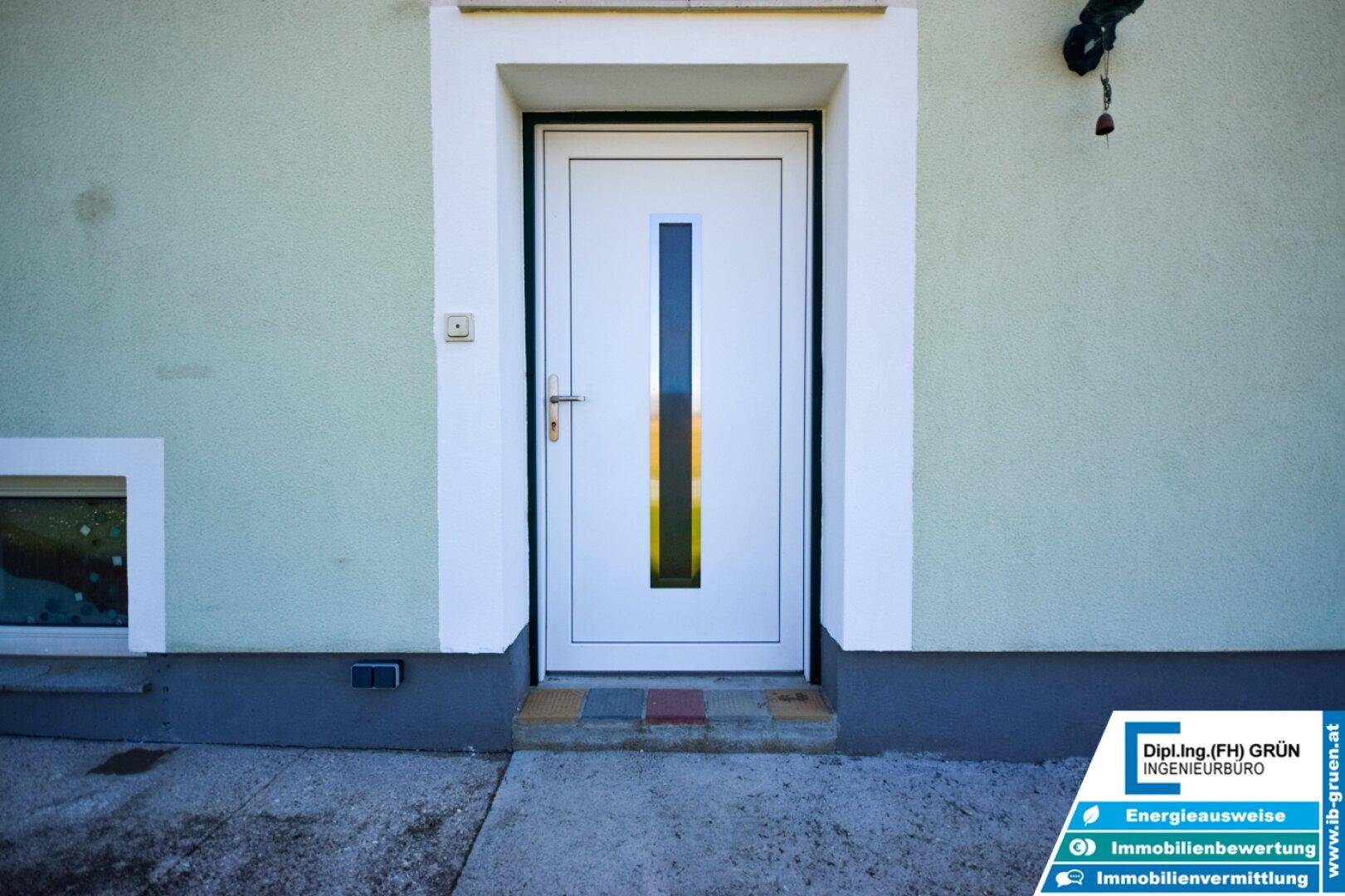 Moderne weiße Eingangstür mit vertikalem Glaseinsatz und schlichtem Rahmen.