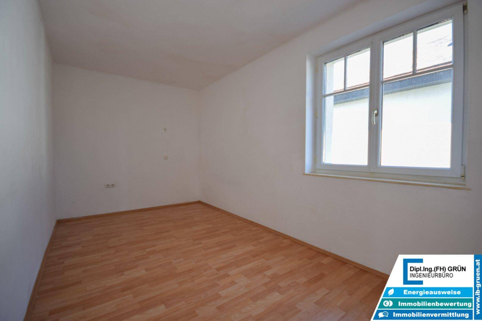 Kleines, helles Zimmer mit Laminatboden und einem Fenster, ideal als Kinder- oder Gästezimmer.