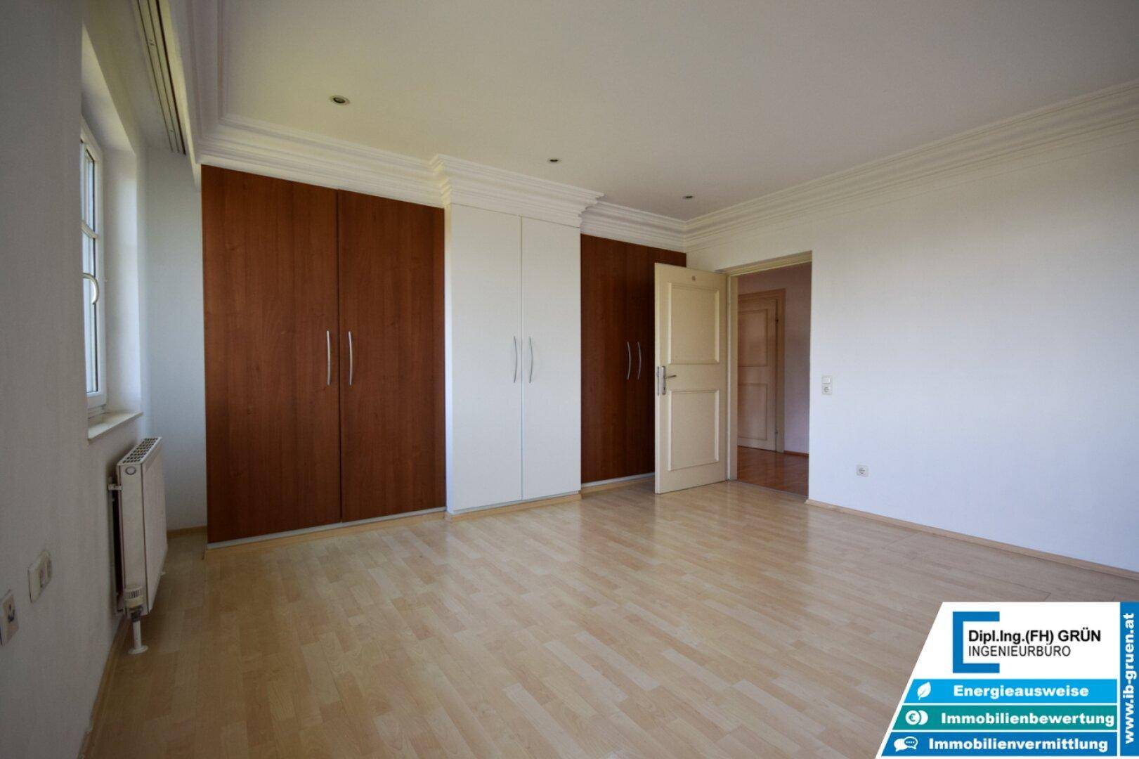 Helles Schlafzimmer mit Laminatboden und praktischen Einbauschränken in Holz- und Weißtönen.