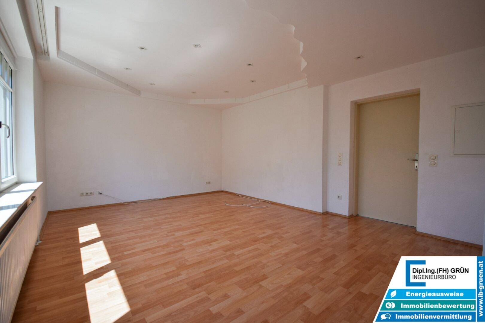 Geräumiges Wohnzimmer mit Laminatboden und moderner Deckenbeleuchtung, bereit zur Einrichtung.