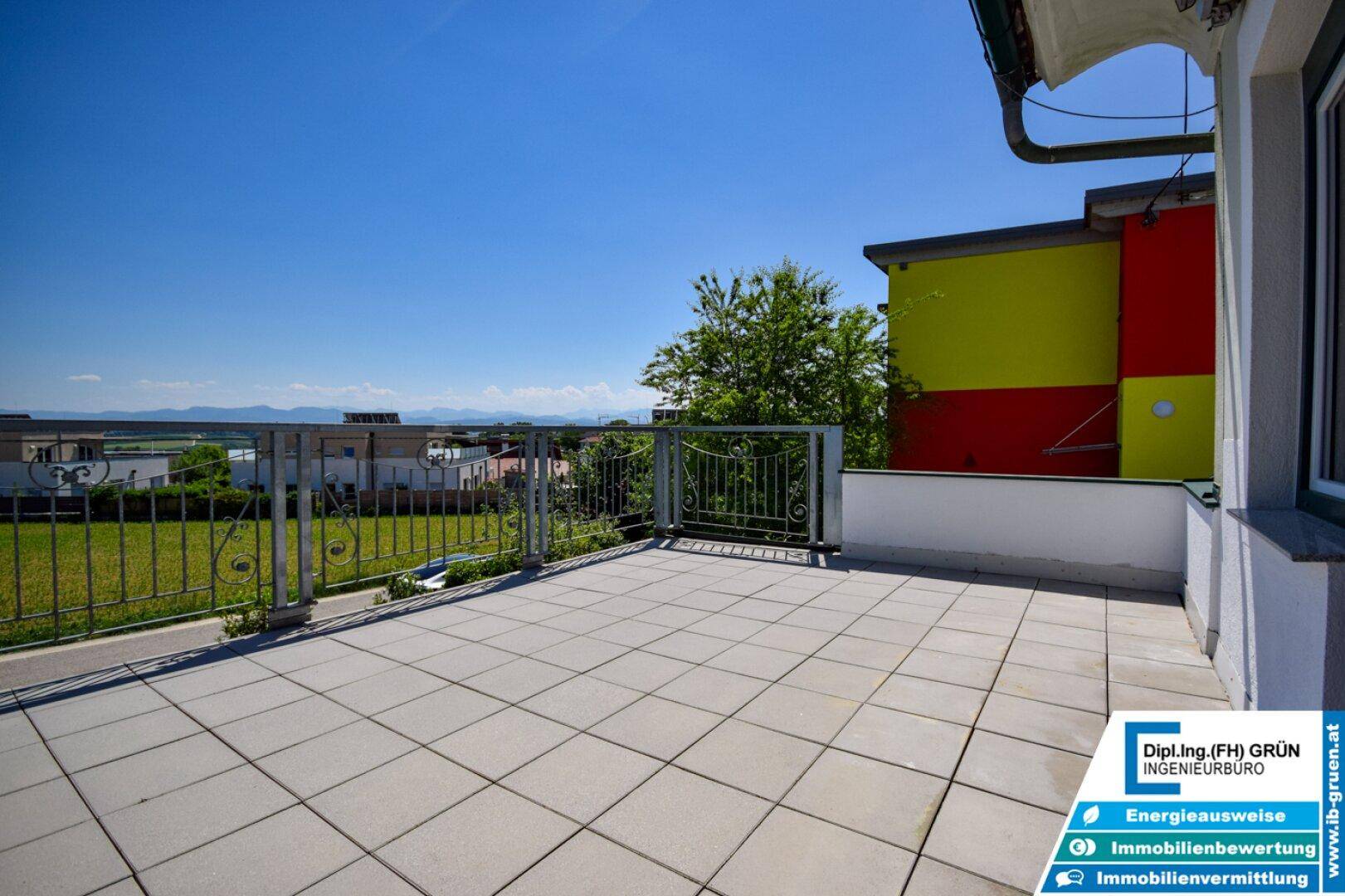 Große geflieste Terrasse mit Metallgeländer und weitem Blick über die Landschaft.