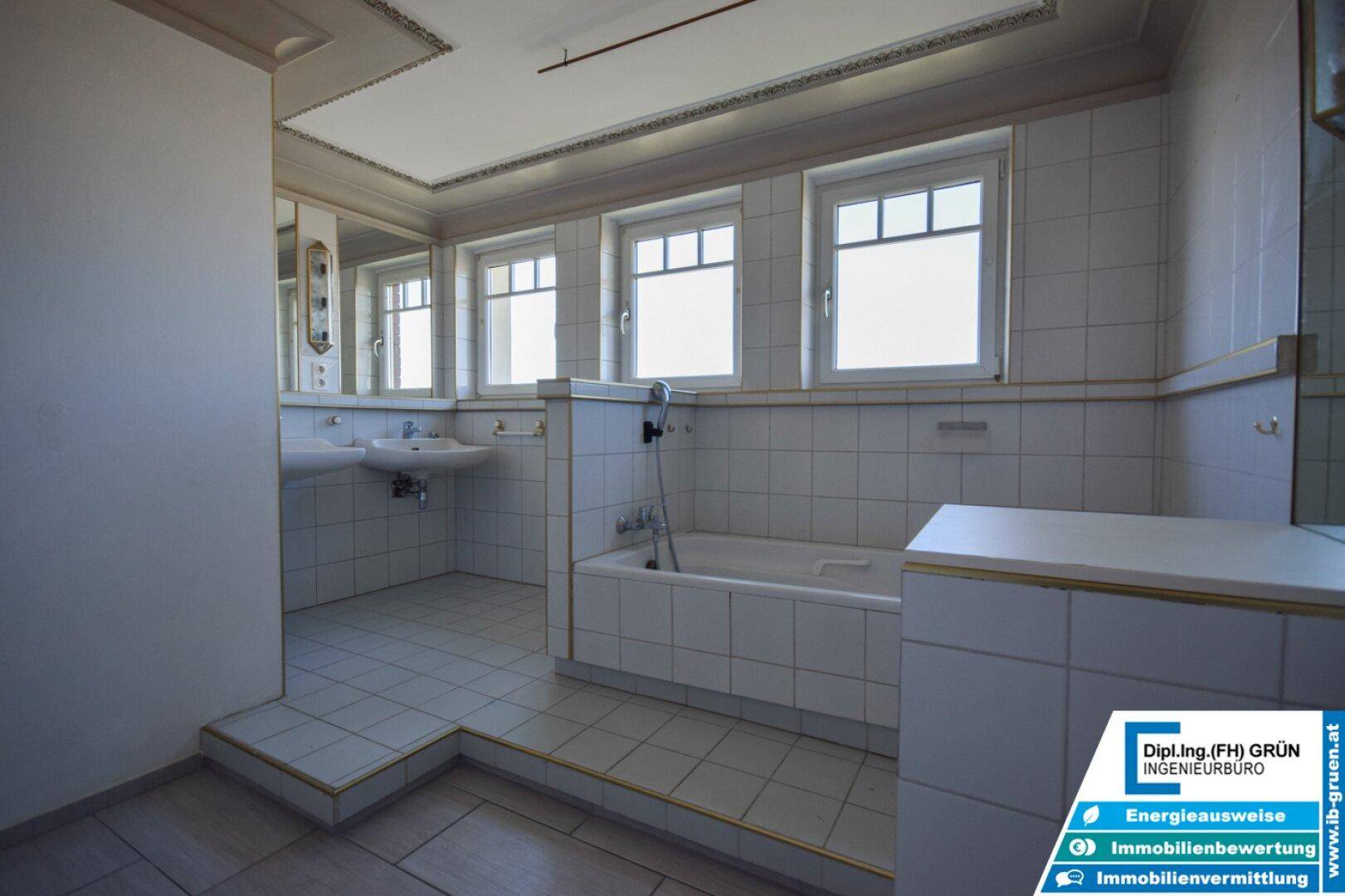 Helles Badezimmer mit Badewanne, Doppelwaschbecken und großen Spiegeln über den Waschtischen.