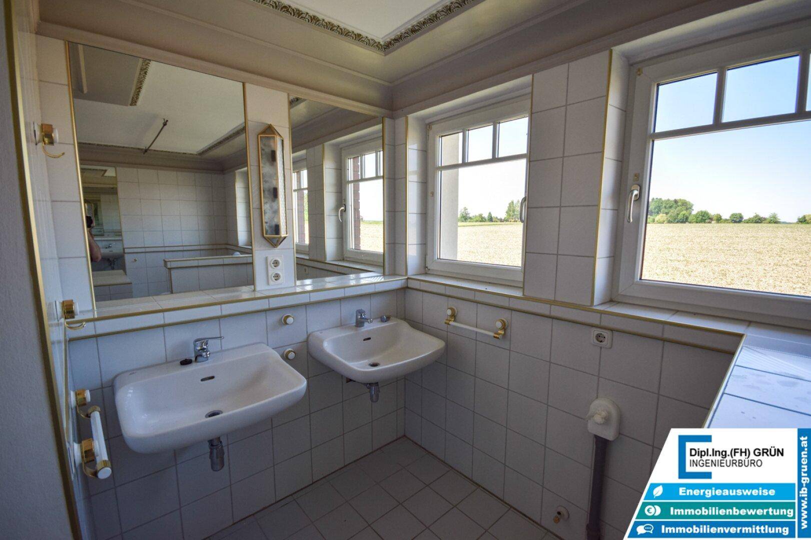 Badezimmer mit Doppelwaschbecken, großen Spiegeln und Blick auf die umliegenden Felder.