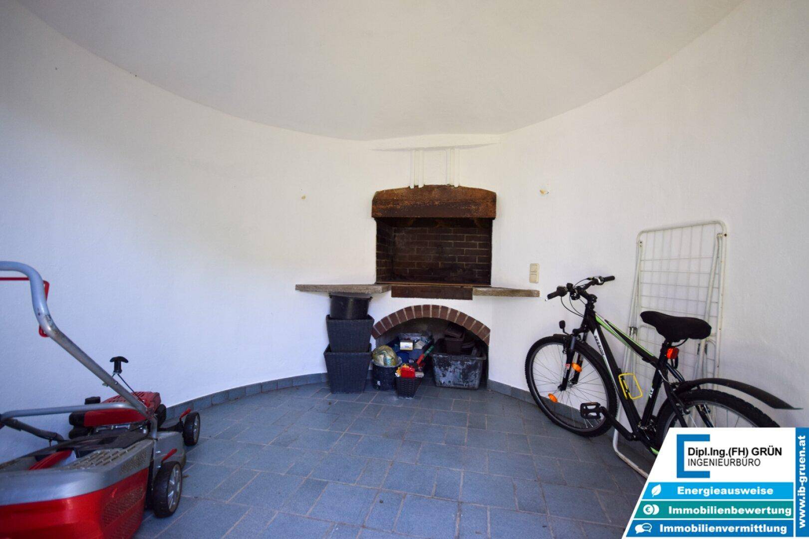 Abstellraum mit gemauertem Grill oder Kamin, Fliesenboden und Stauraum für Gartengeräte.
