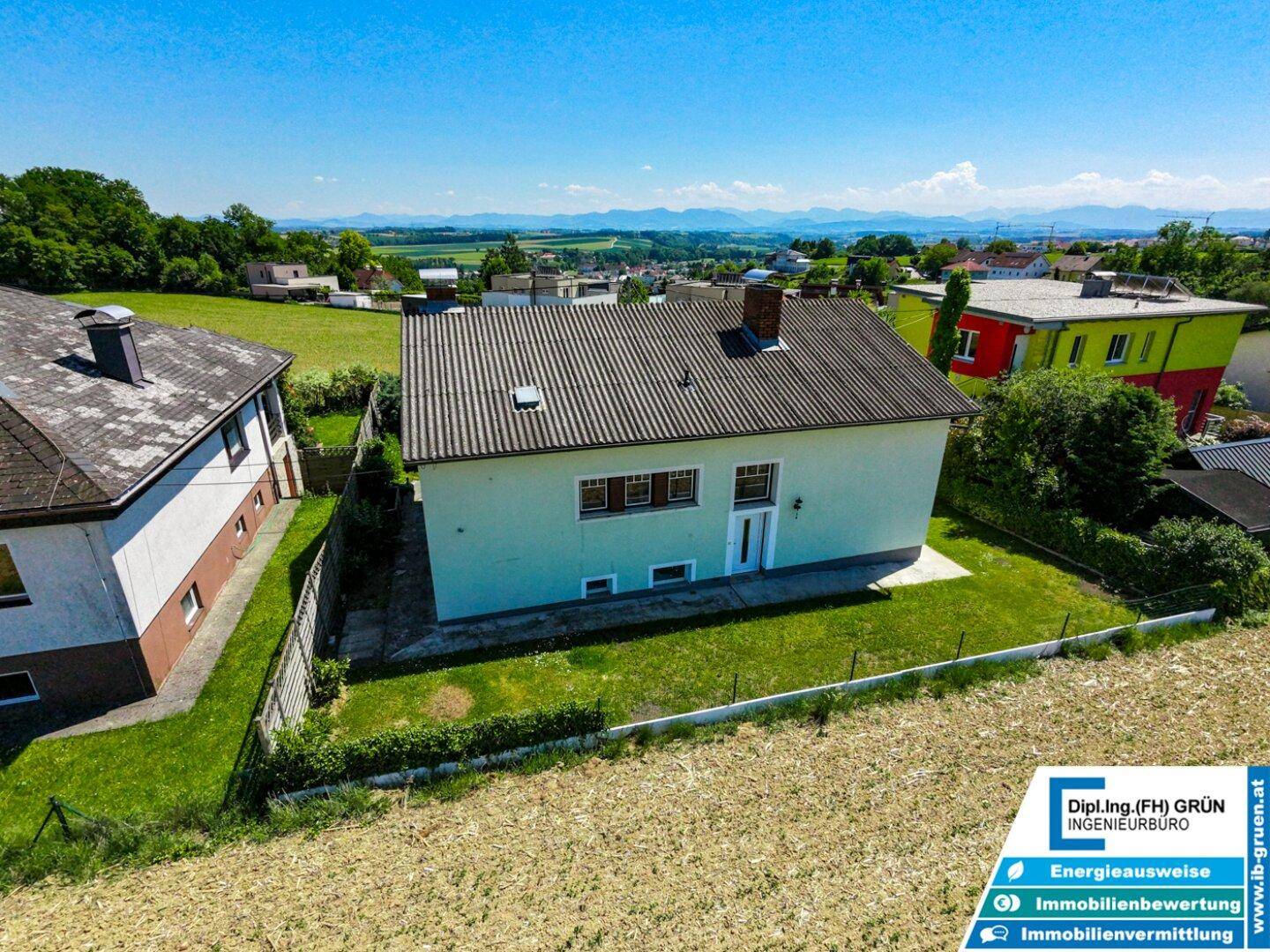 Luftaufnahme des Hauses mit Garten und angrenzenden Feldern unter blauem Himmel.