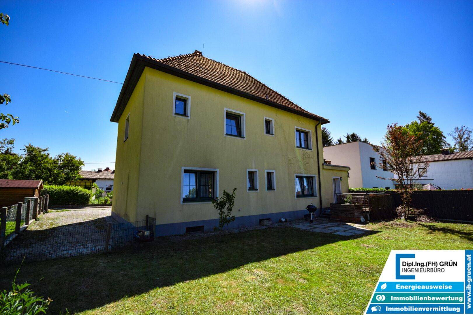 Seitenansicht des Hauses mit großem Rasenbereich und sonnigem Garten.
