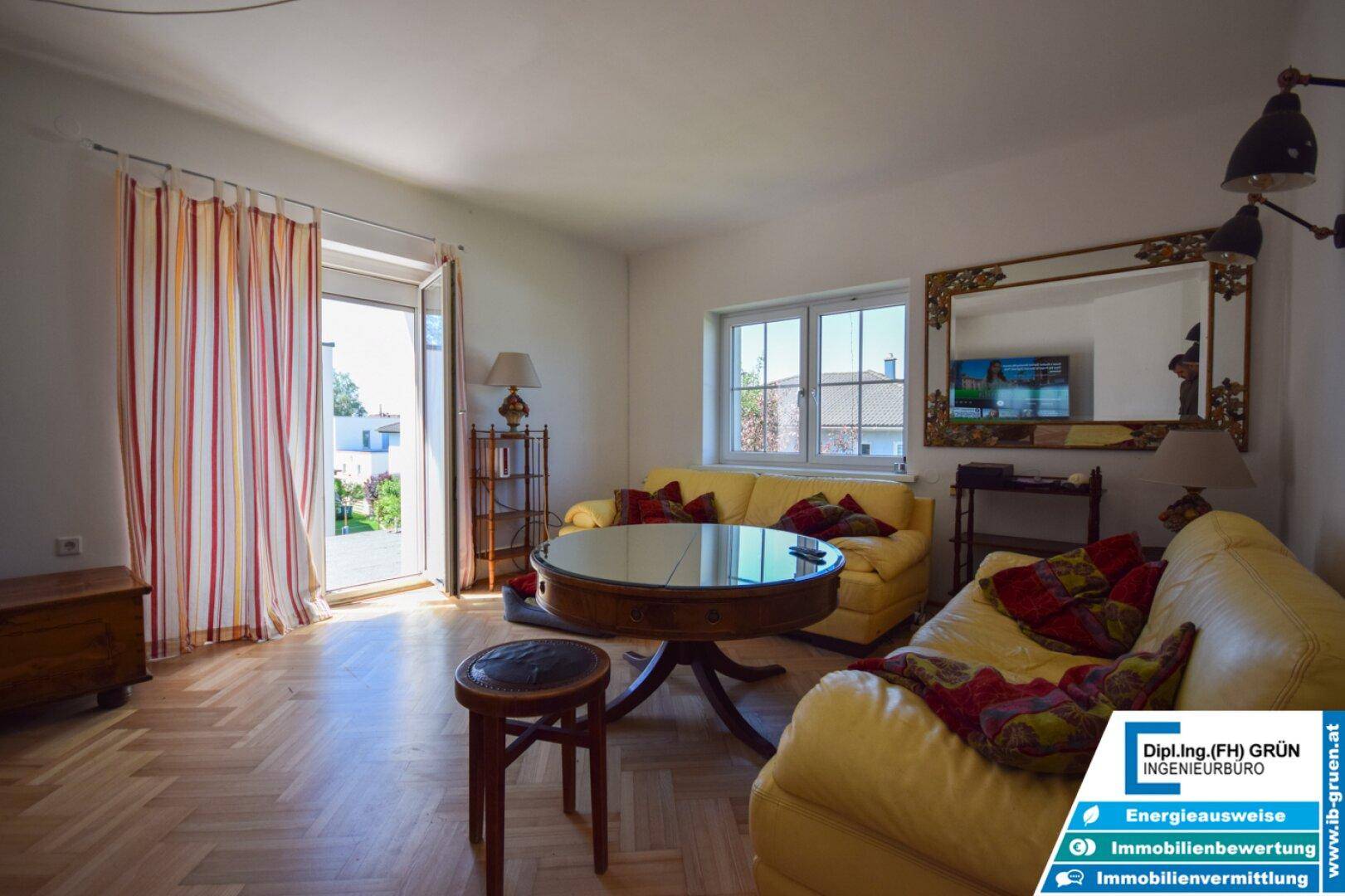 Gemütliches Wohnzimmer mit gelben Sofas, Holzboden und Zugang zu einem Außenbereich.