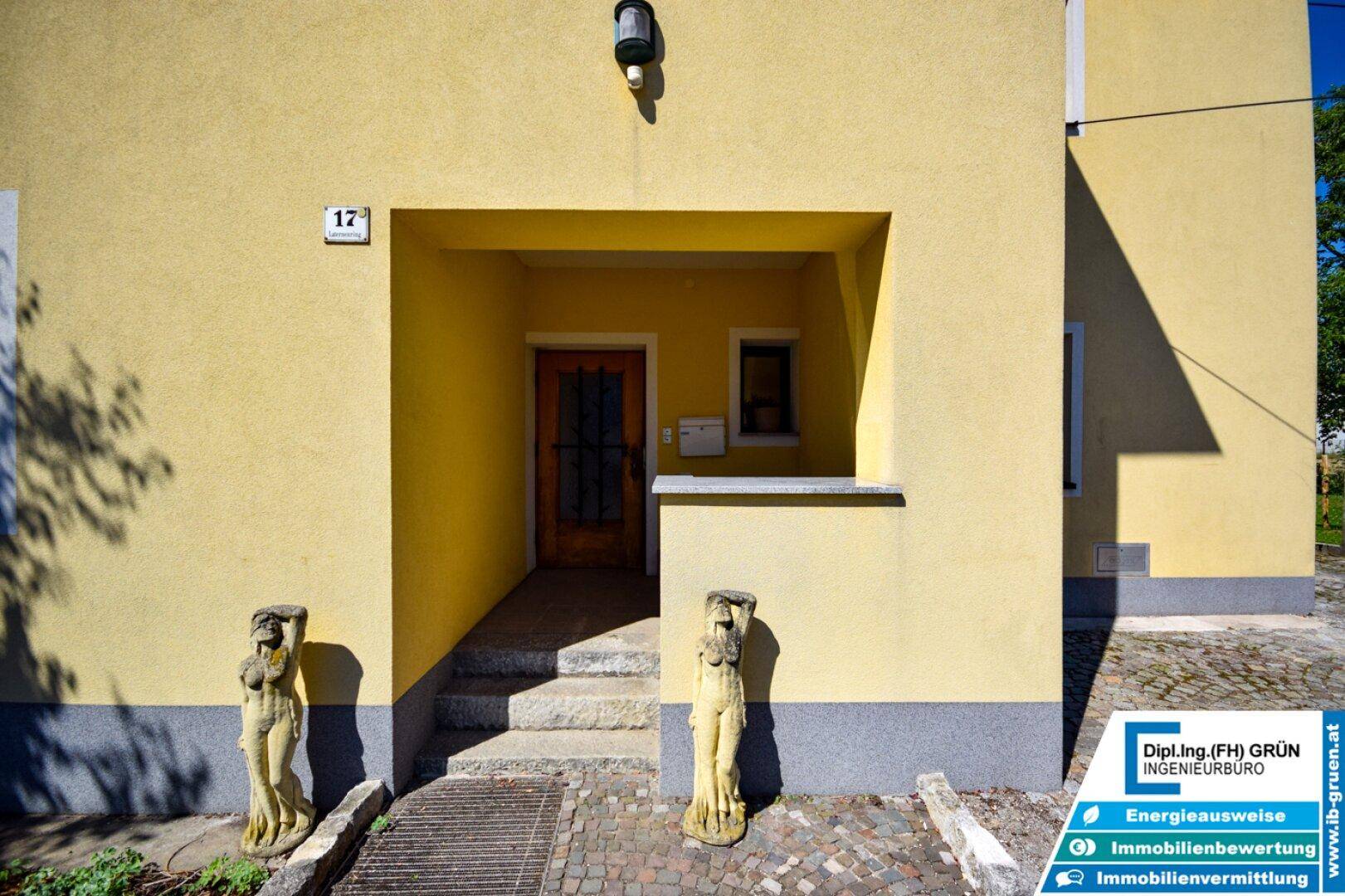 Eingangsbereich des Hauses mit überdachtem Zugang und dekorativen Statuen.