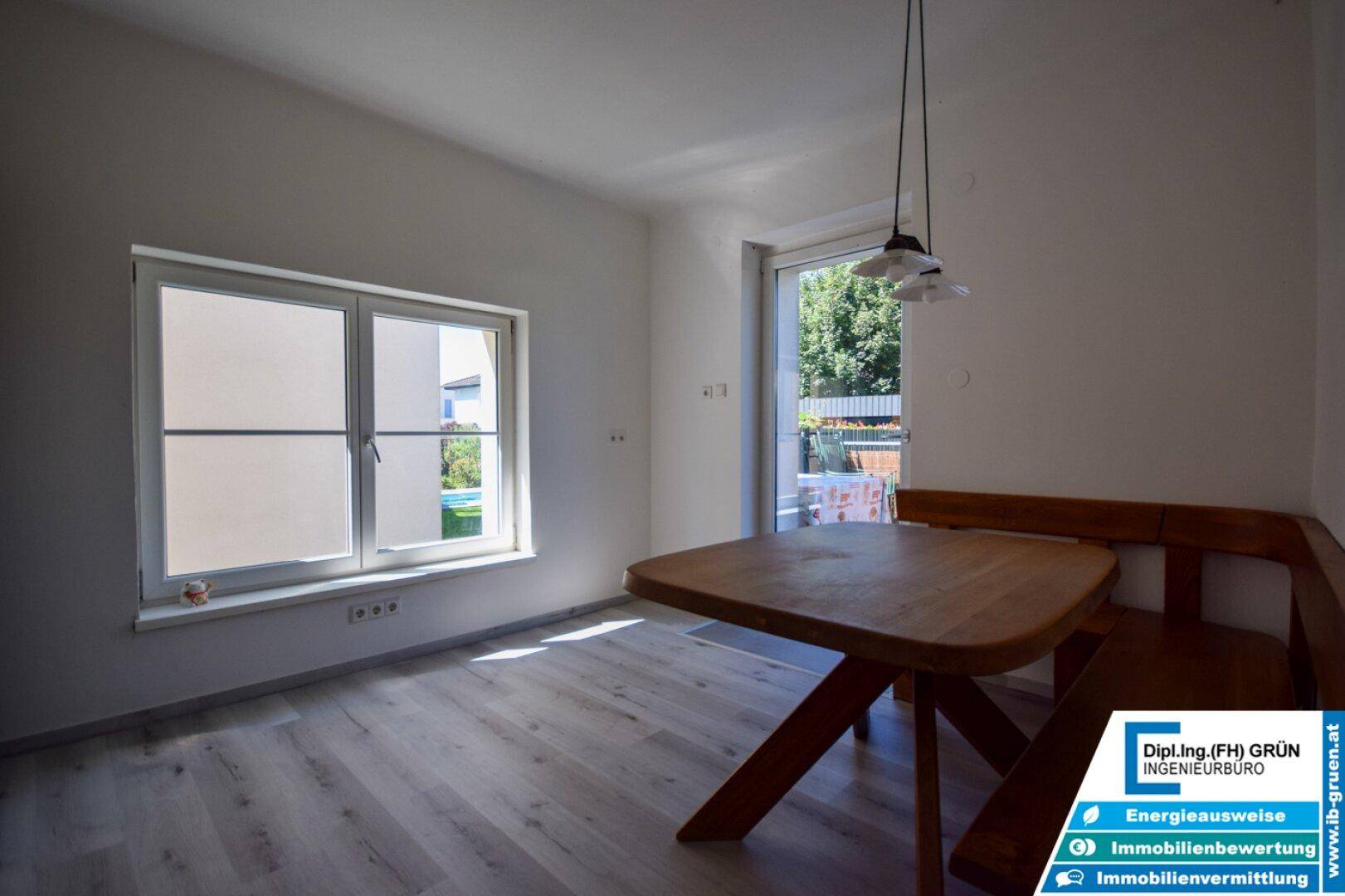 Essbereich in der Küche mit Holztisch, Bank und hellem Laminatboden.