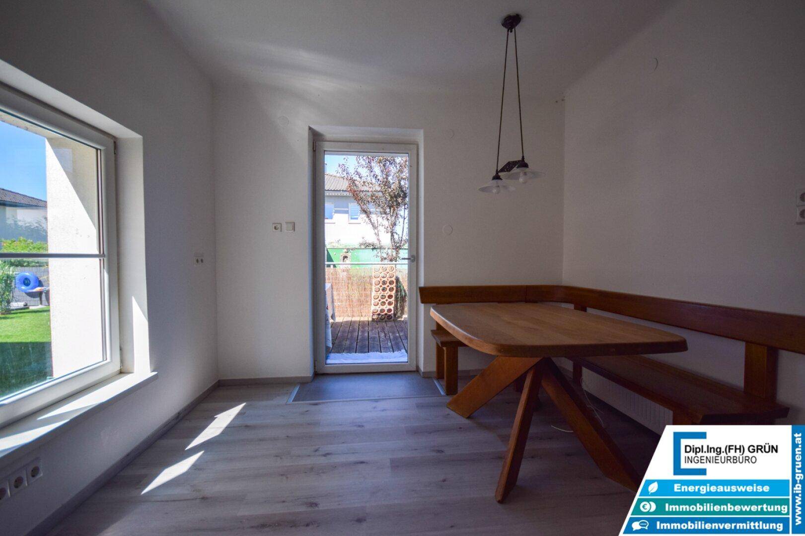 Heller Essbereich in der Küche mit Holztisch, Bank und Zugang zum Außenbereich.