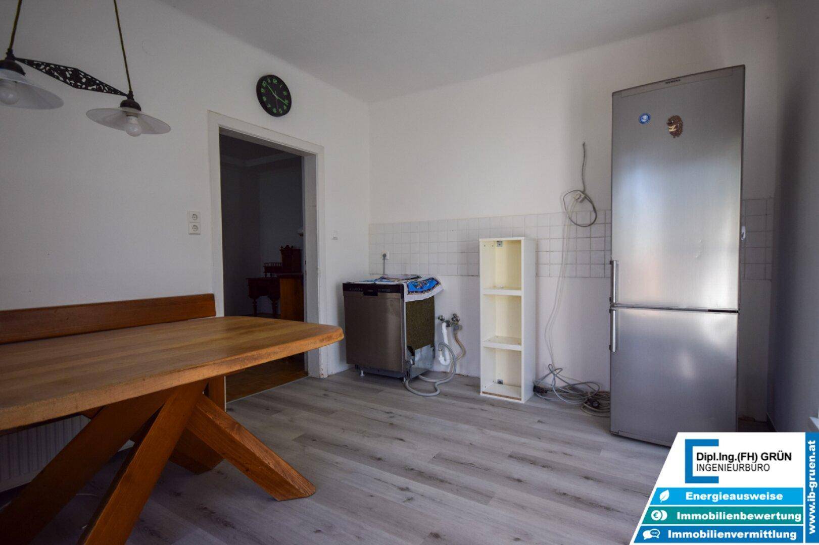 Küche mit Essbereich, Kühlschrank und hellem Laminatboden.