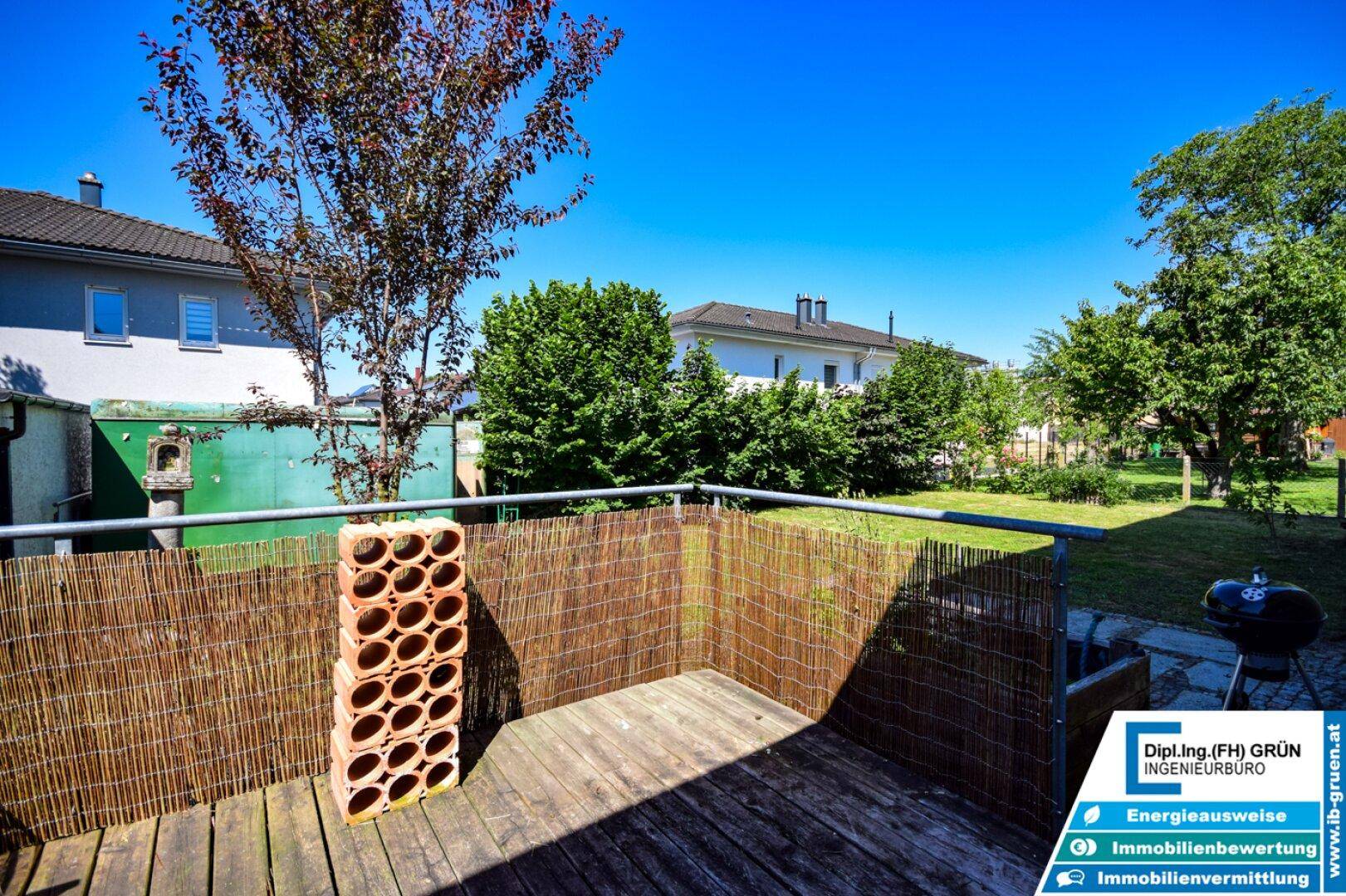 Holzterrasse mit Sichtschutz und Blick auf den grünen Gartenbereich.