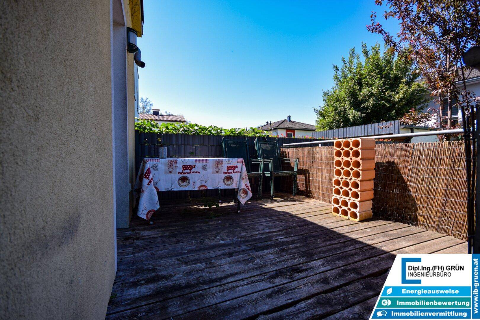 Gemütliche Holzterrasse mit Tisch und Stühlen, ideal für Mahlzeiten im Freien.