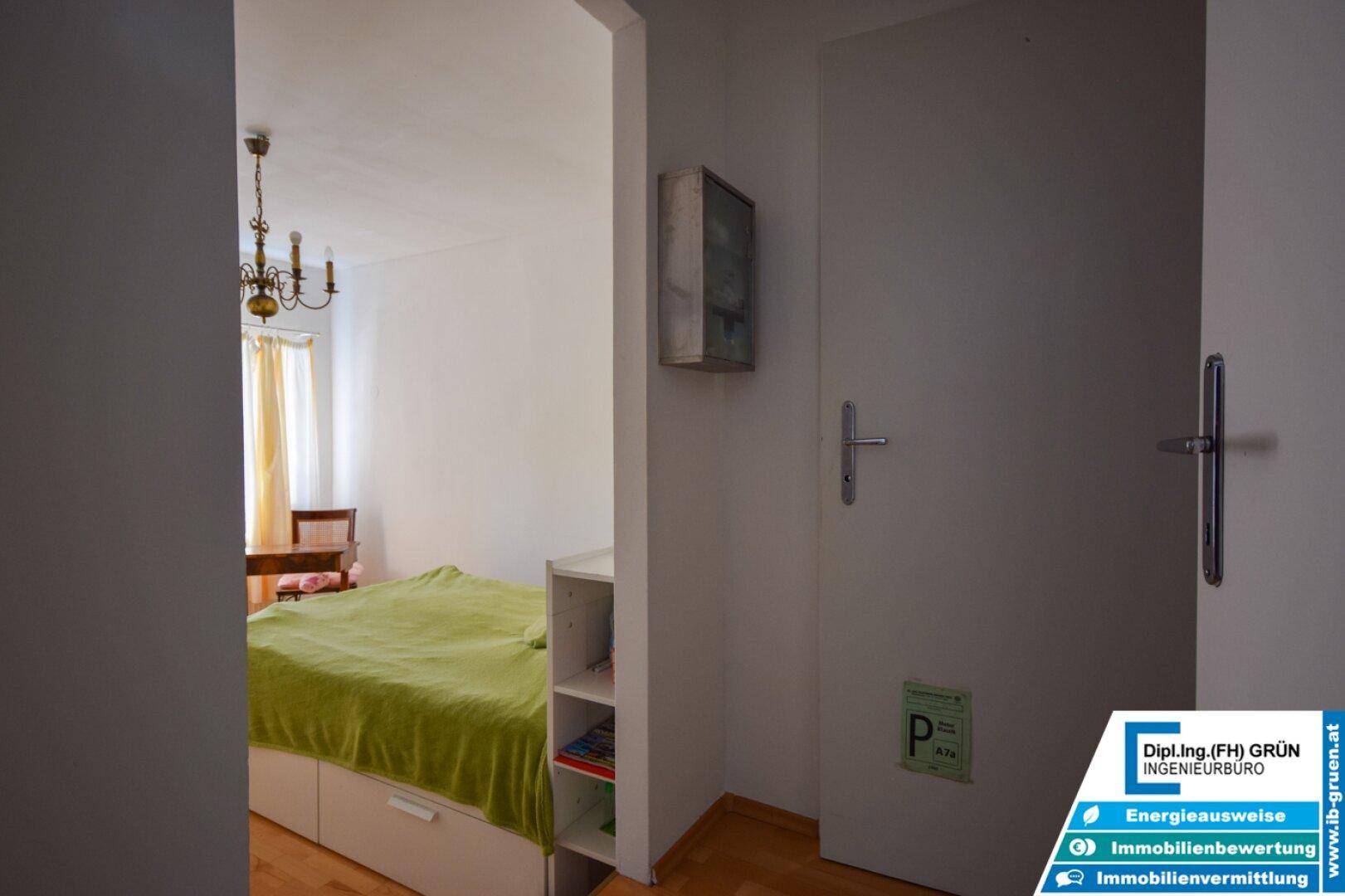 Schlafzimmer mit Bett und Stauraum, sichtbar durch eine offene Tür.