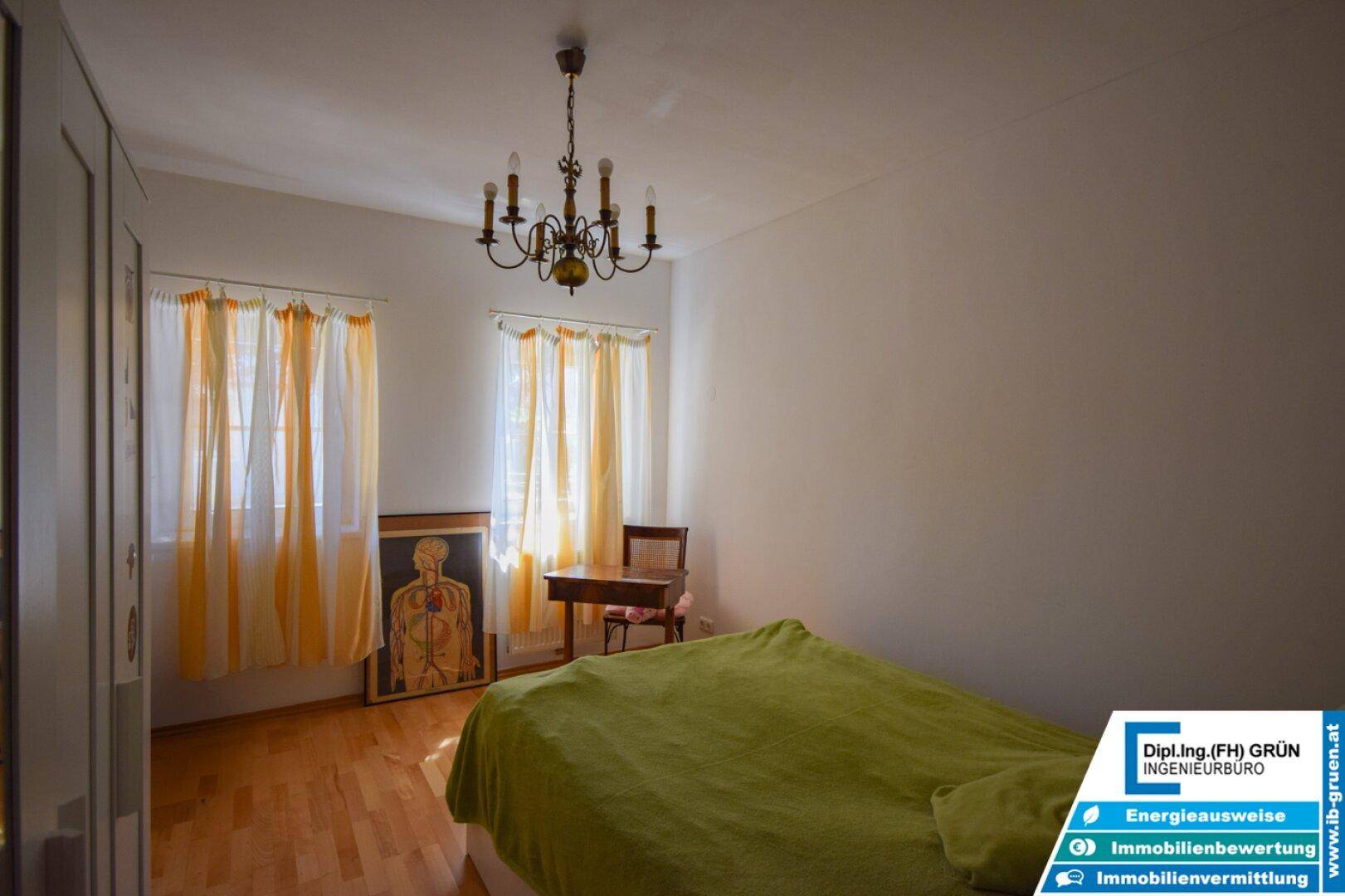 Helles Schlafzimmer mit Parkettboden, gelben Vorhängen und einem klassischen Kronleuchter.
